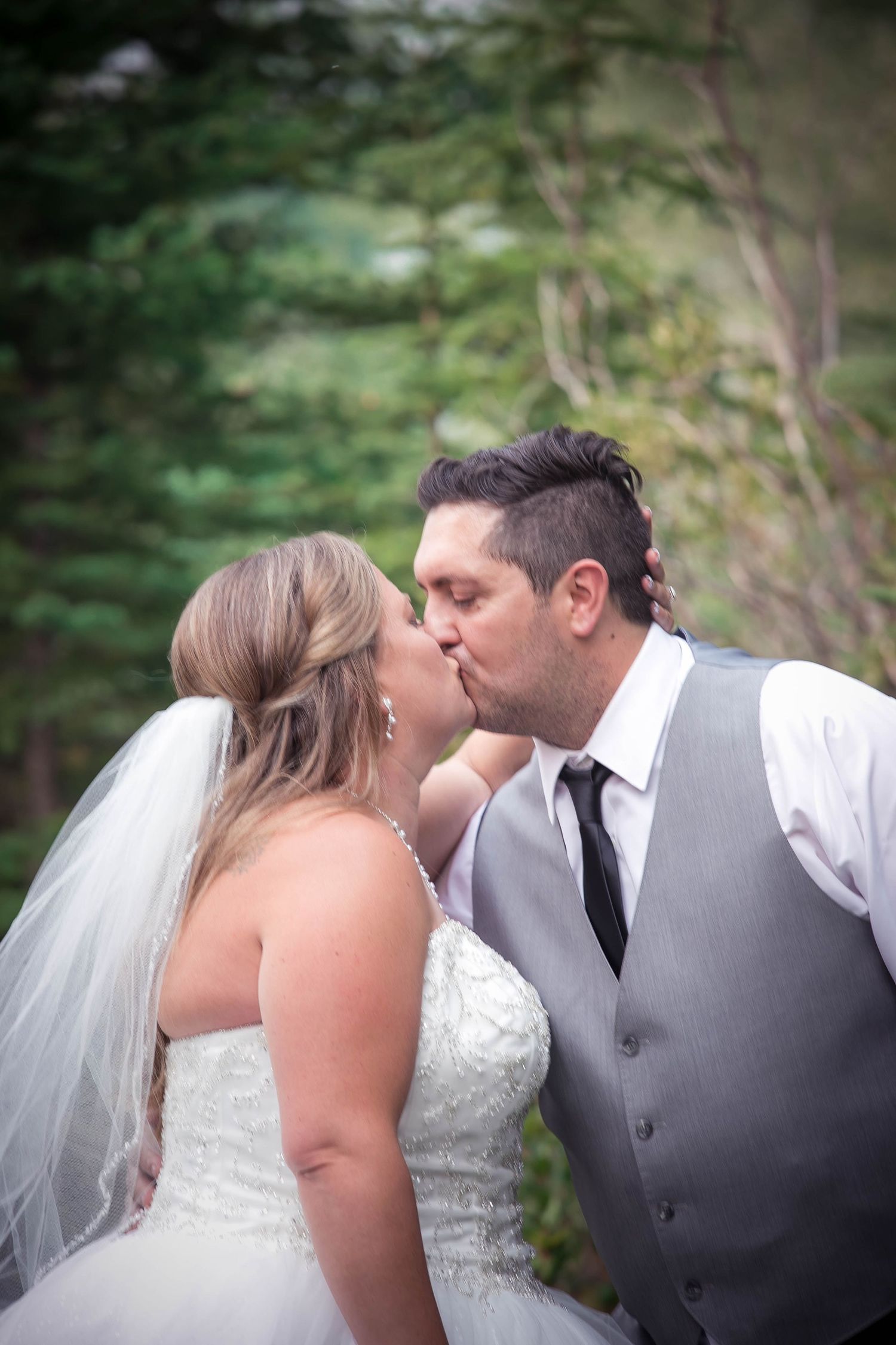 A tender moment shared between newlyweds in a forest setting.