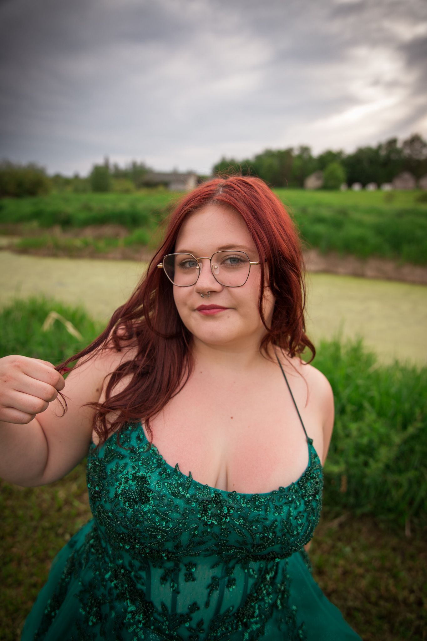 Close-up portrait in emerald sequined gown against natural outdoor backdrop.