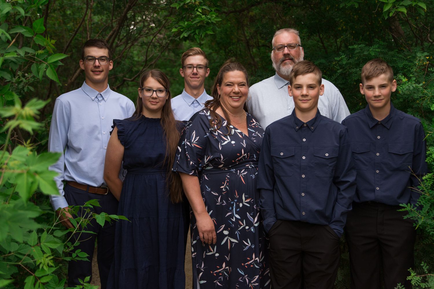 Group portrait of family members in formal attire standing together in a garden setting.