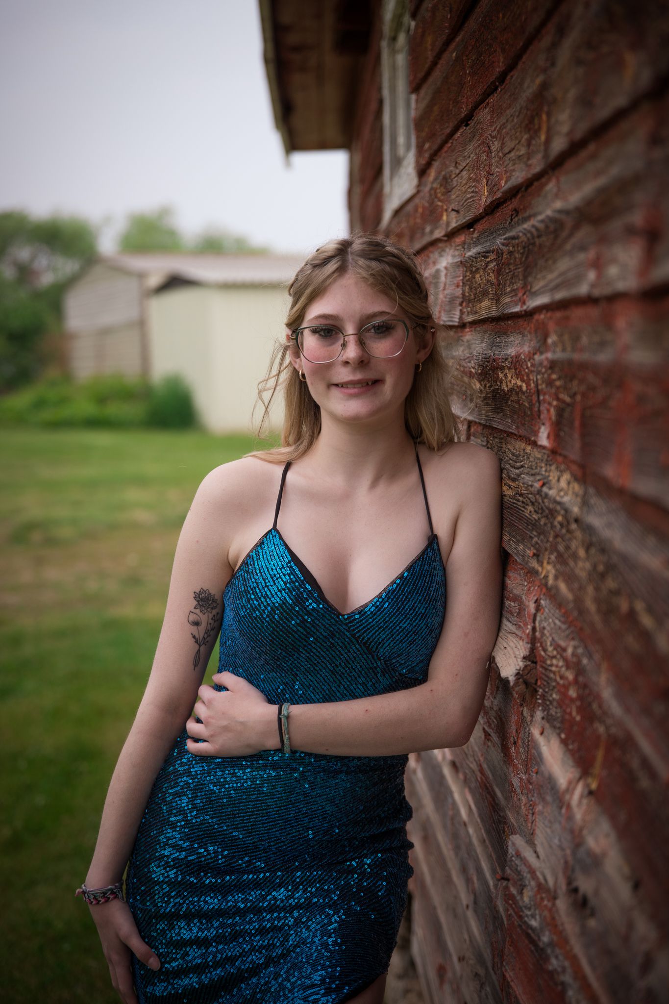 A sparkling blue formal dress is showcased against a rustic brick wall backdrop.