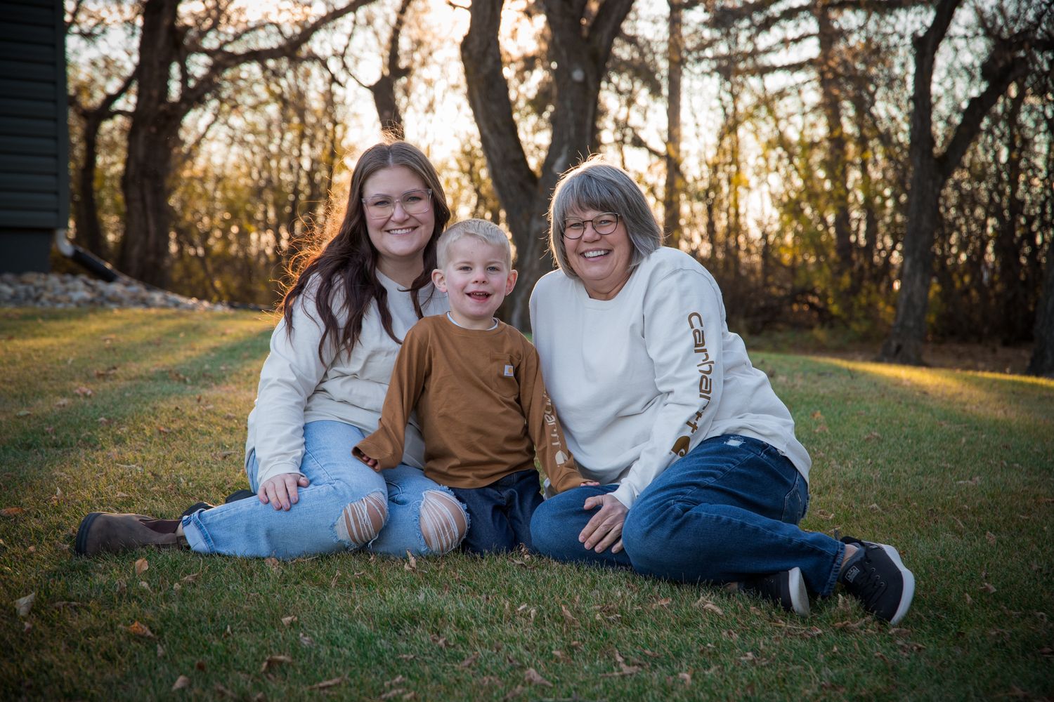 Family members laying on grass together during an outdoor autumn photoshoot.