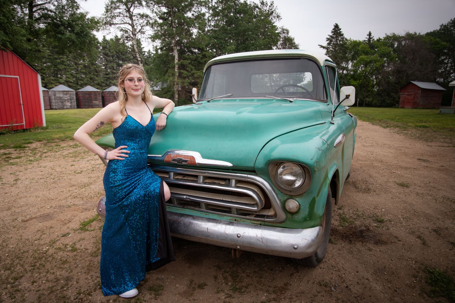 Classic mint green car posed with formal attire in rustic outdoor setting.