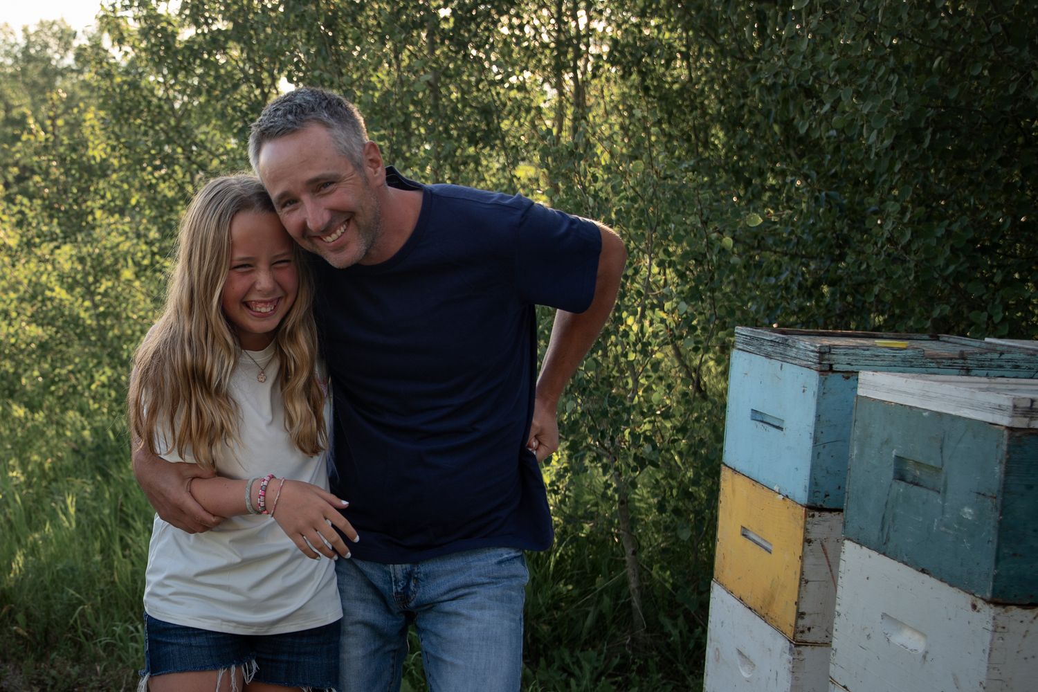 A couple shares a happy moment together near beehive boxes at sunset in a rural setting.