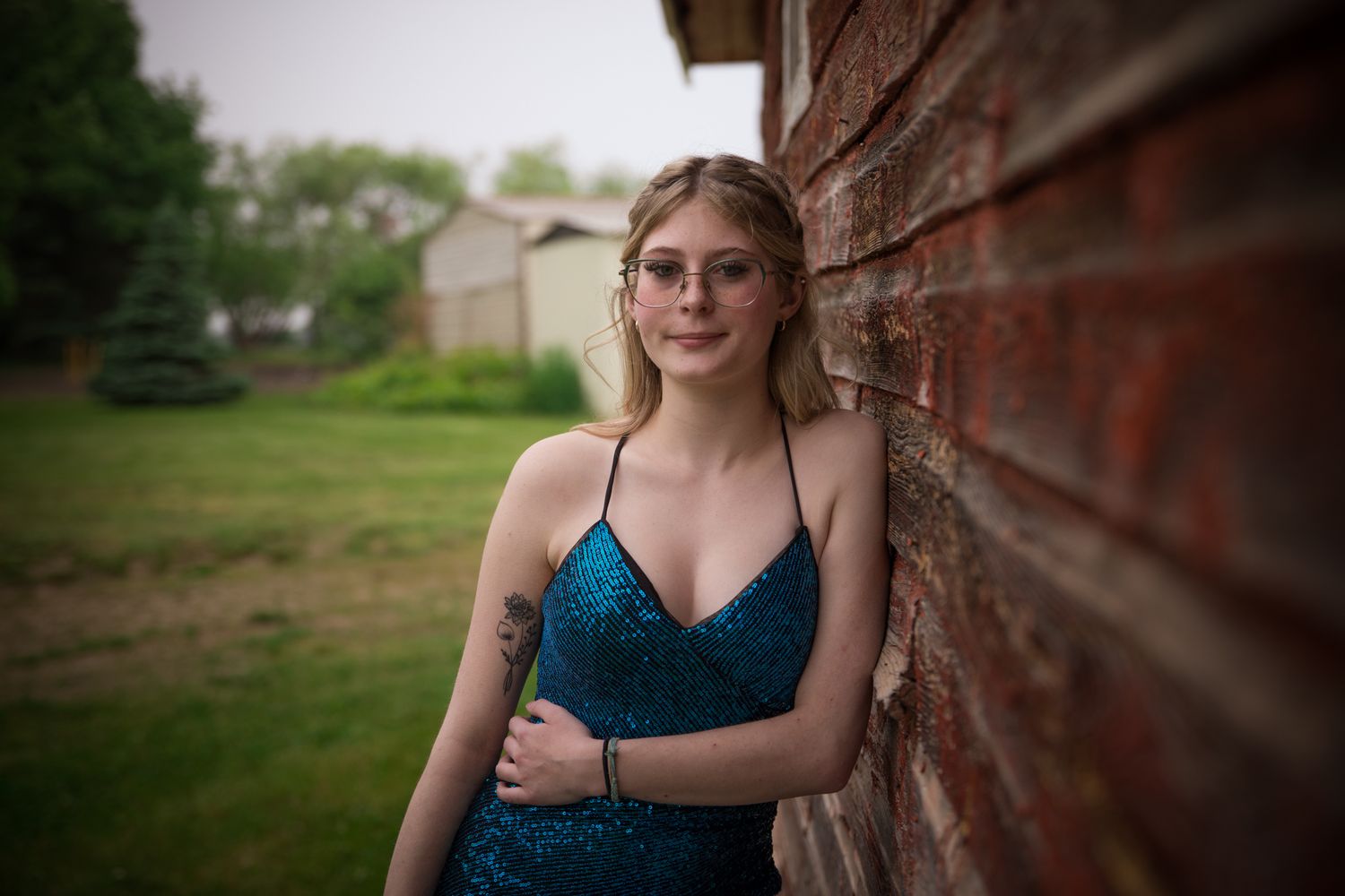 A formal portrait session featuring a blue sequined dress against textured brick walls.