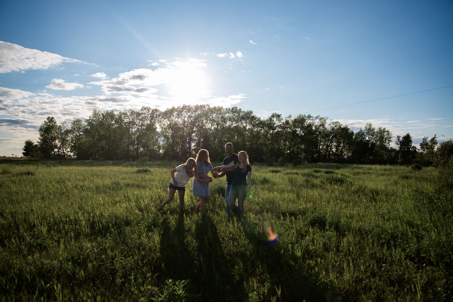 People gathered in a green summer field under bright blue skies with white clouds.
