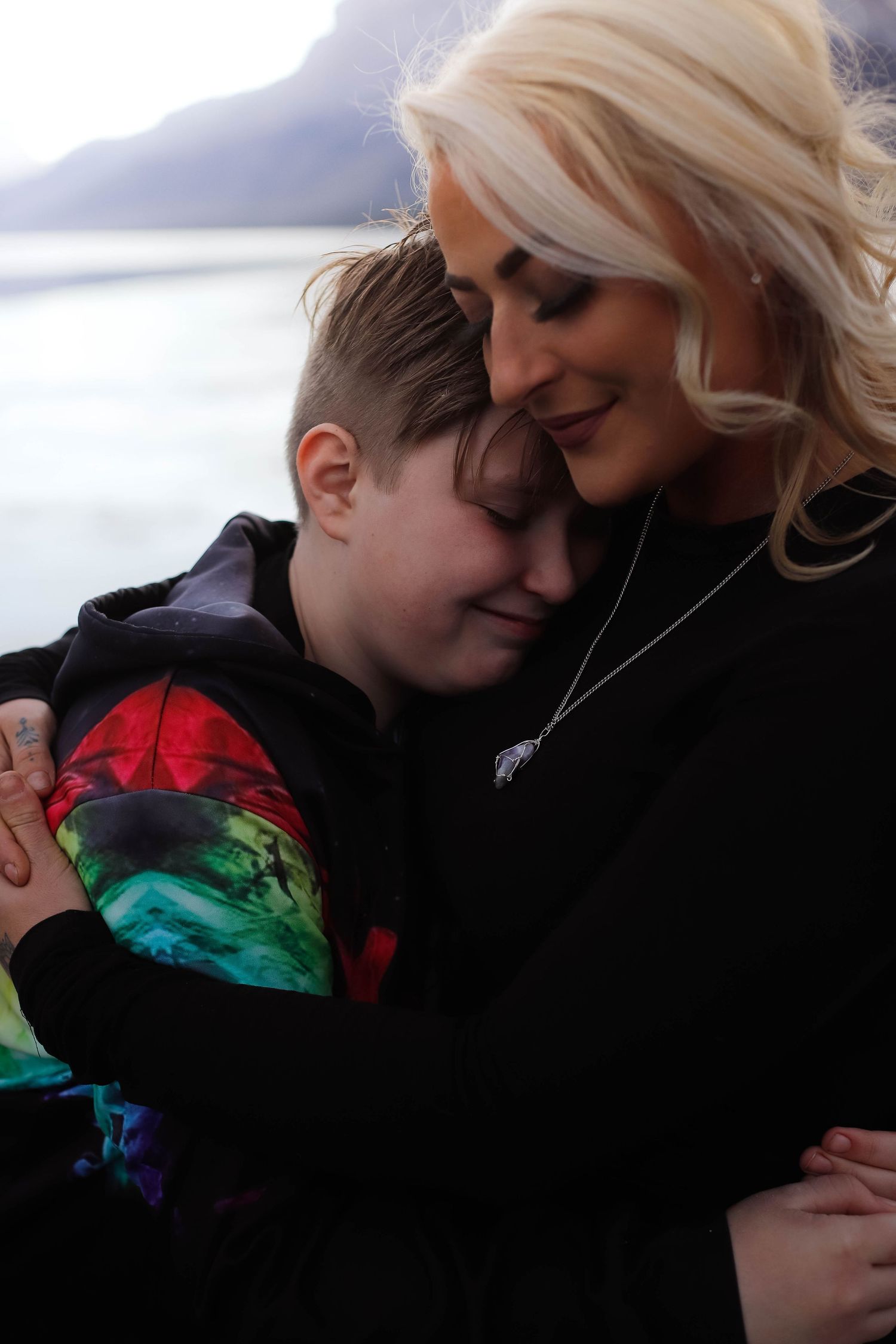 Mother and child share a tender embrace wearing casual black clothing.
