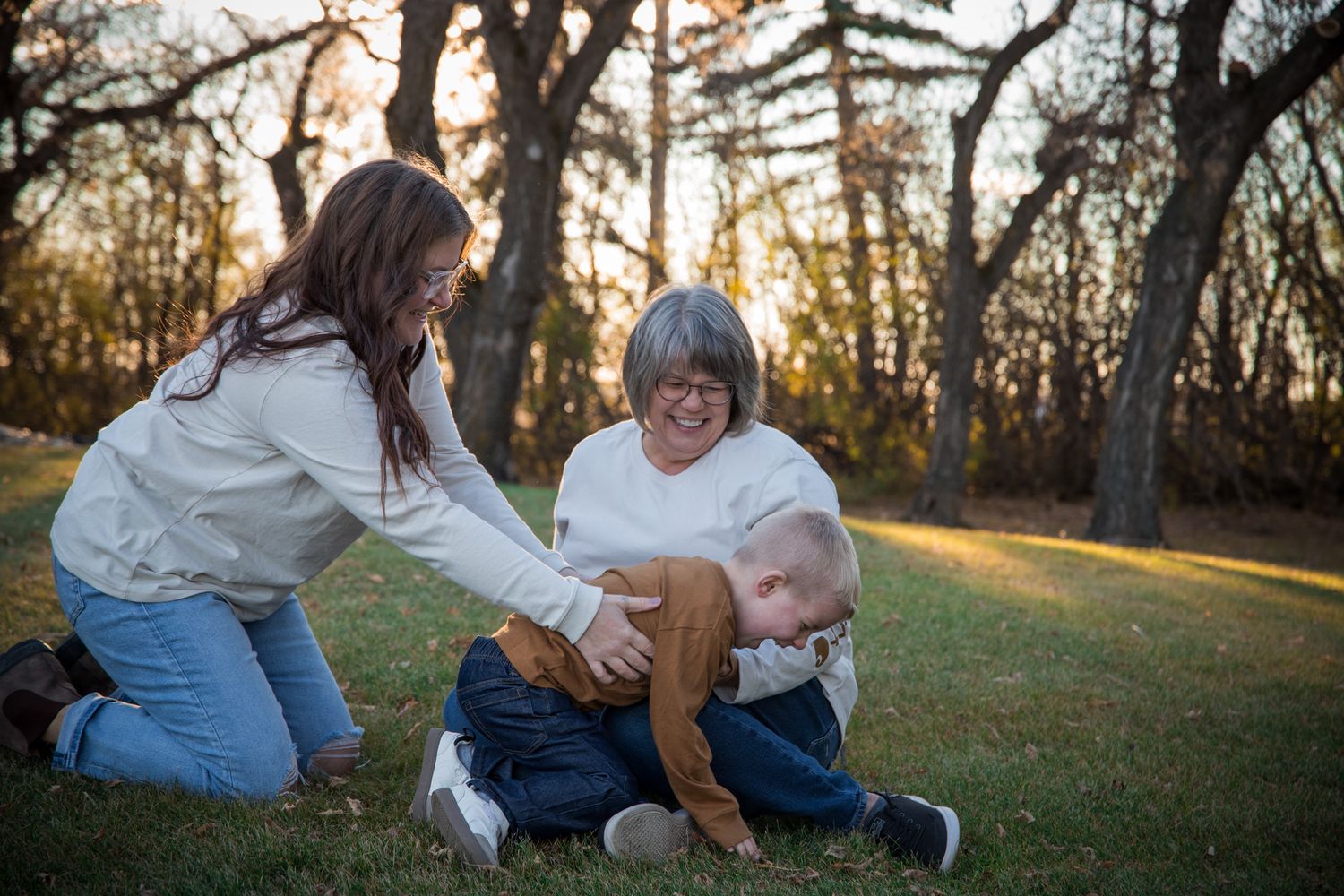 Playful family photoshoot moments captured on grass with natural autumn backdrop.
