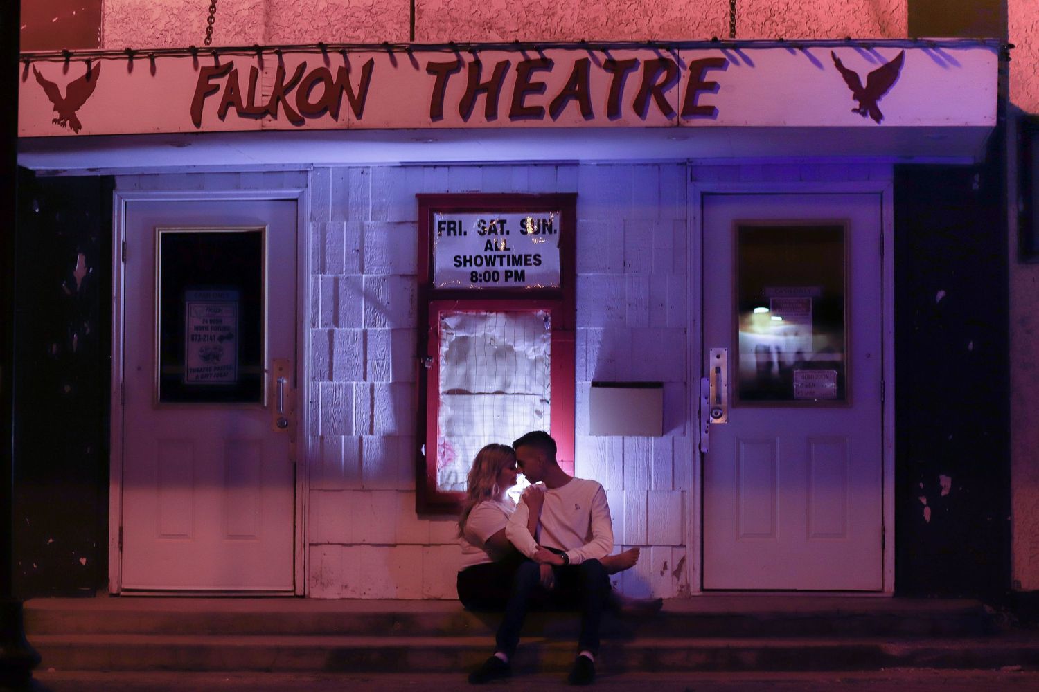 The exterior of Falcon Theatre at night with red-tinted lighting and signage.