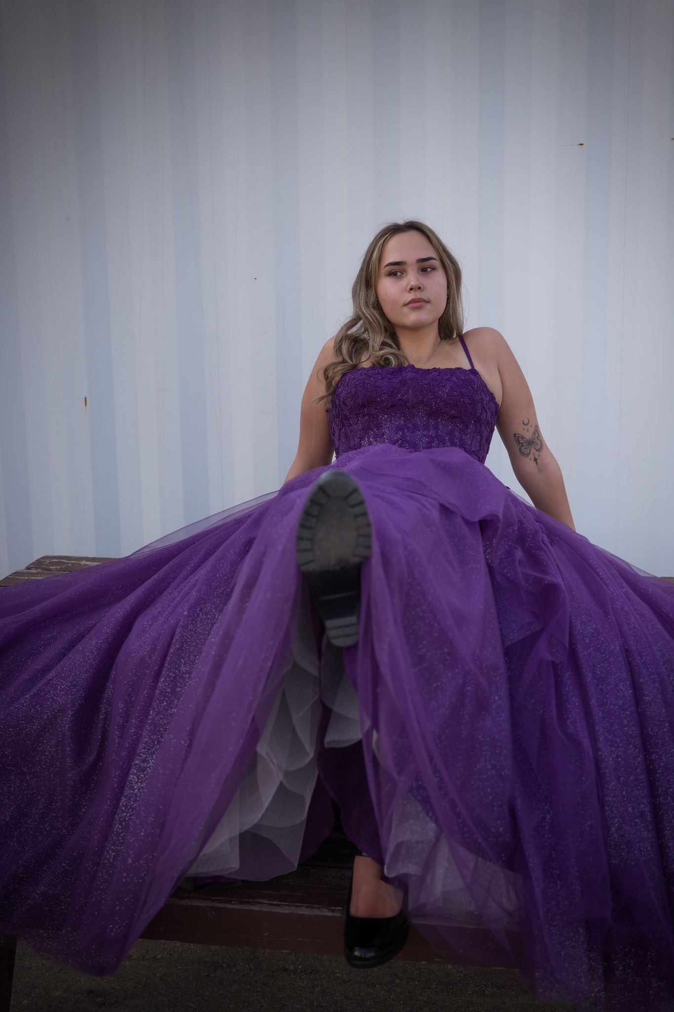 A flowing purple formal dress photographed against a white industrial backdrop.