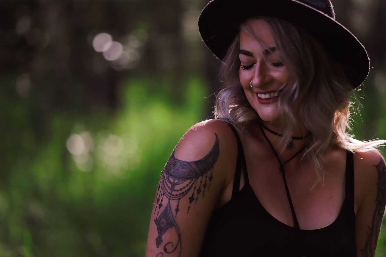 Outdoor portraits with wide-brimmed hat and natural lighting in forest setting.