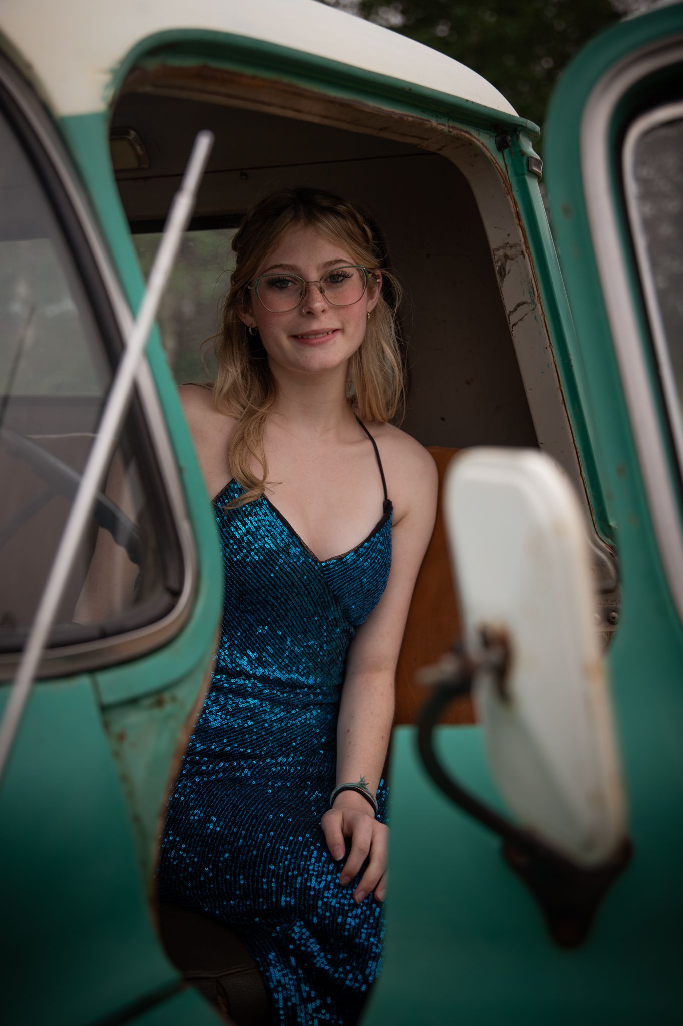 Vintage mint green car serves as backdrop for glamorous blue sequined dress portrait.