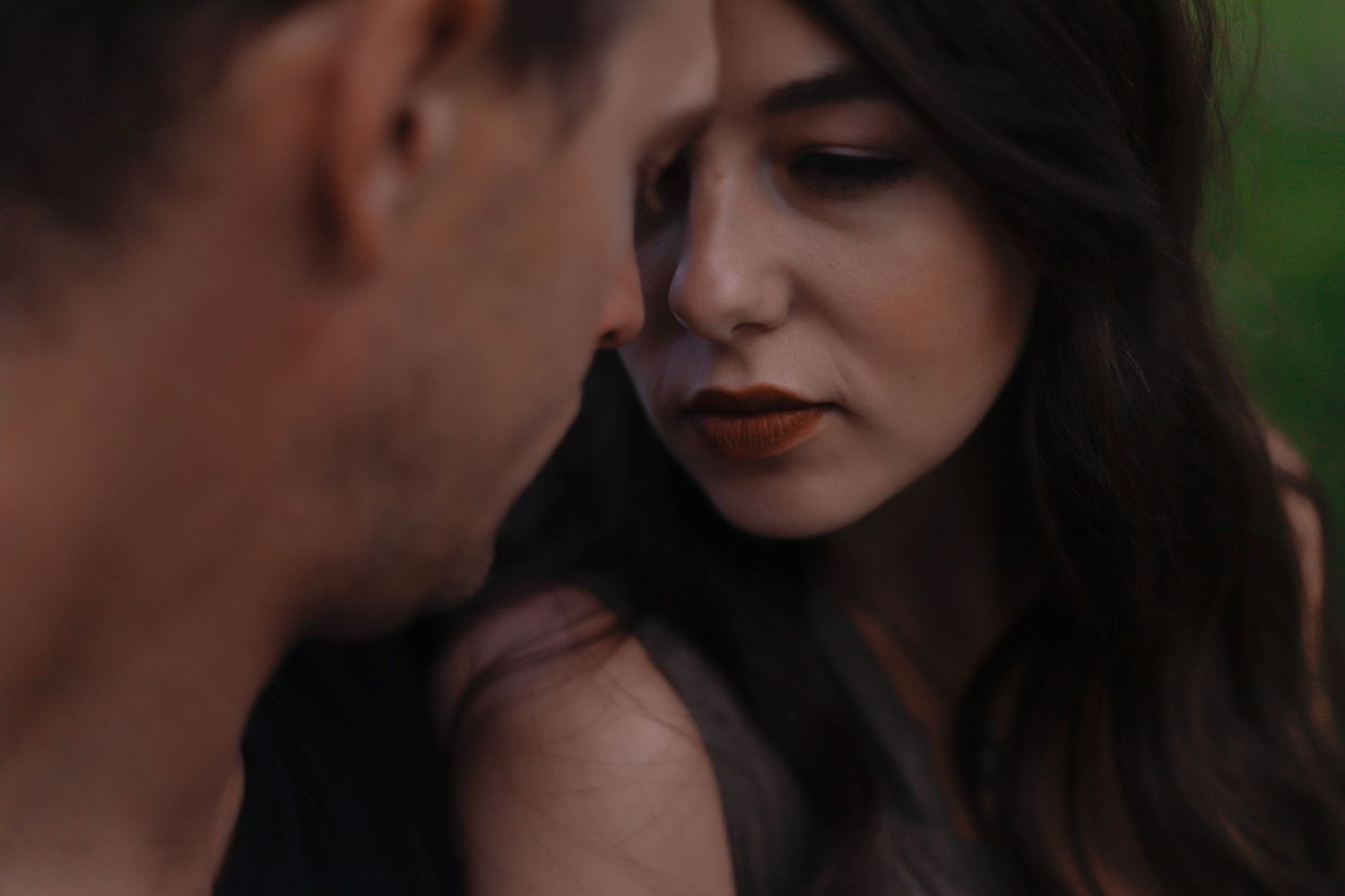 Romantic couple sharing an intimate moment against a blurred natural background.