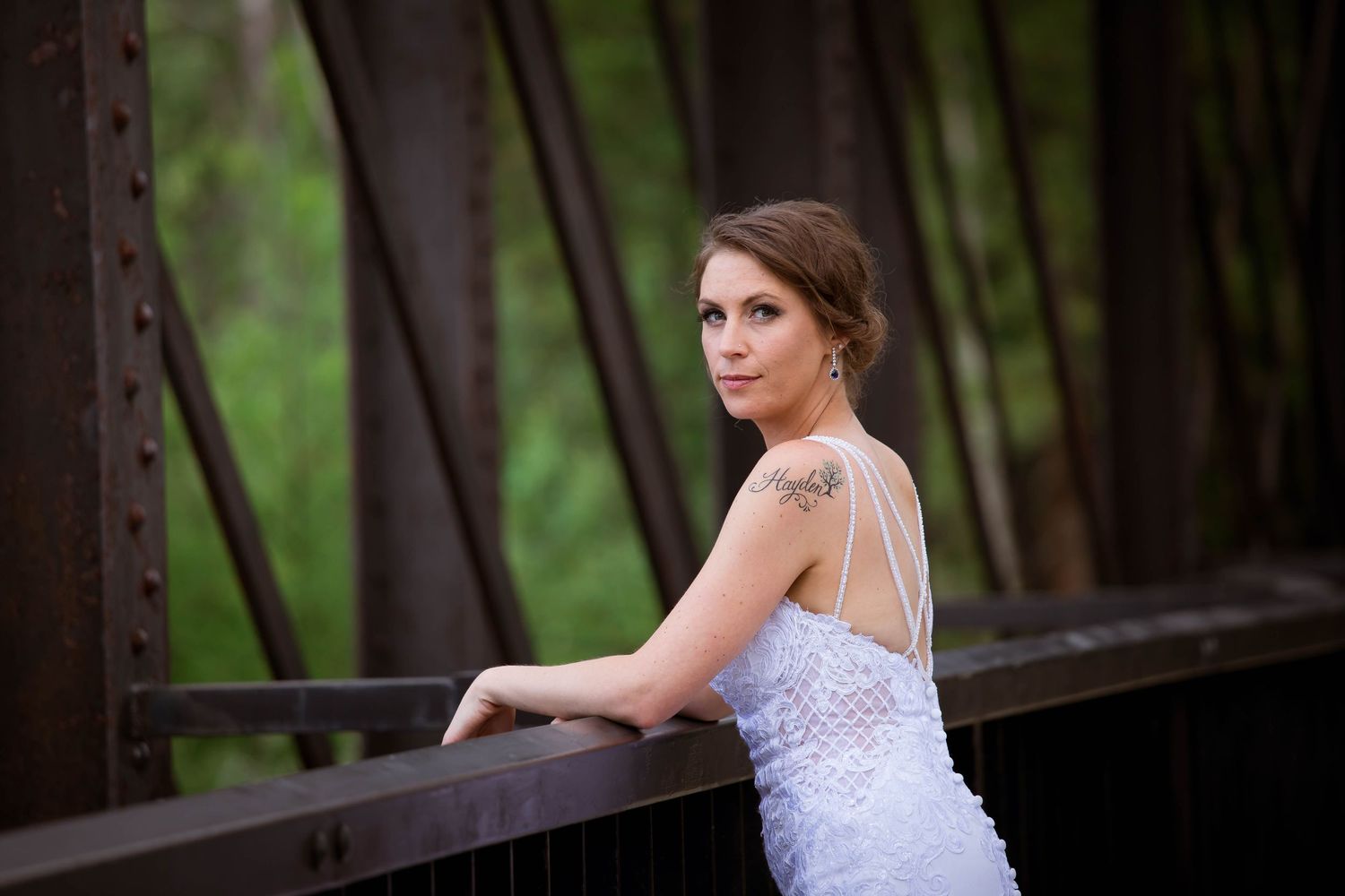 Elegant bridal portraits taken on a rustic wooden bridge with natural forest background.