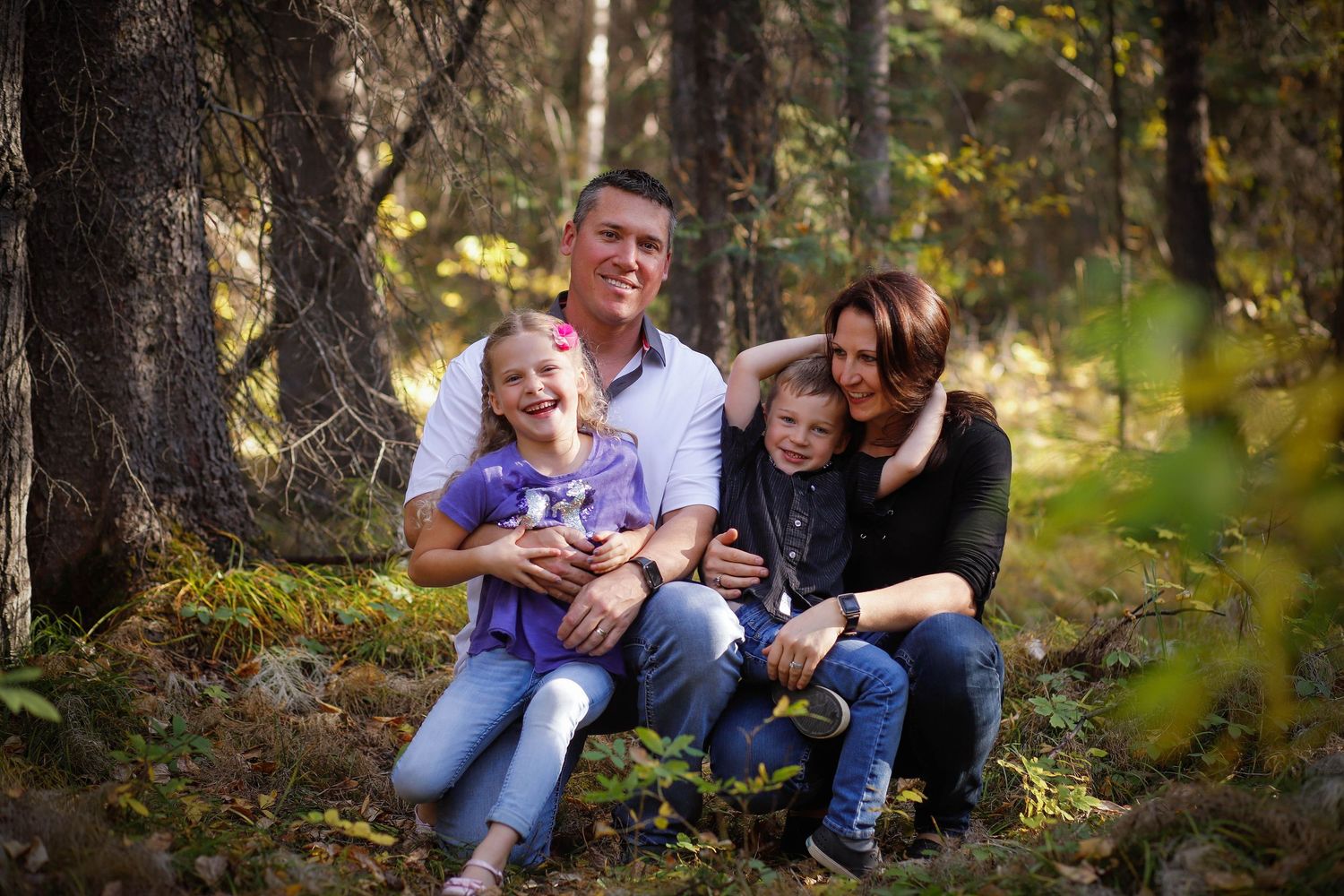 Family portrait session in a forest setting with natural lighting and fall colors.