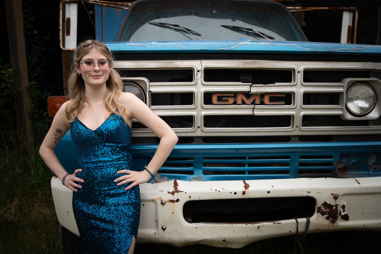 Classic GMC truck grille and front end details shown in closeup with blue dress in frame.