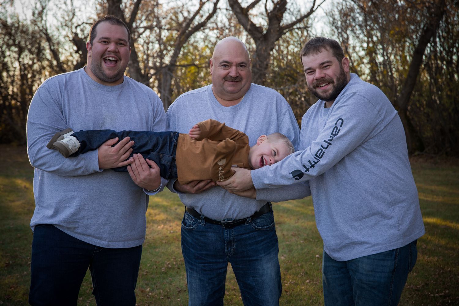Candid family portrait with everyone laughing and having fun outdoors.