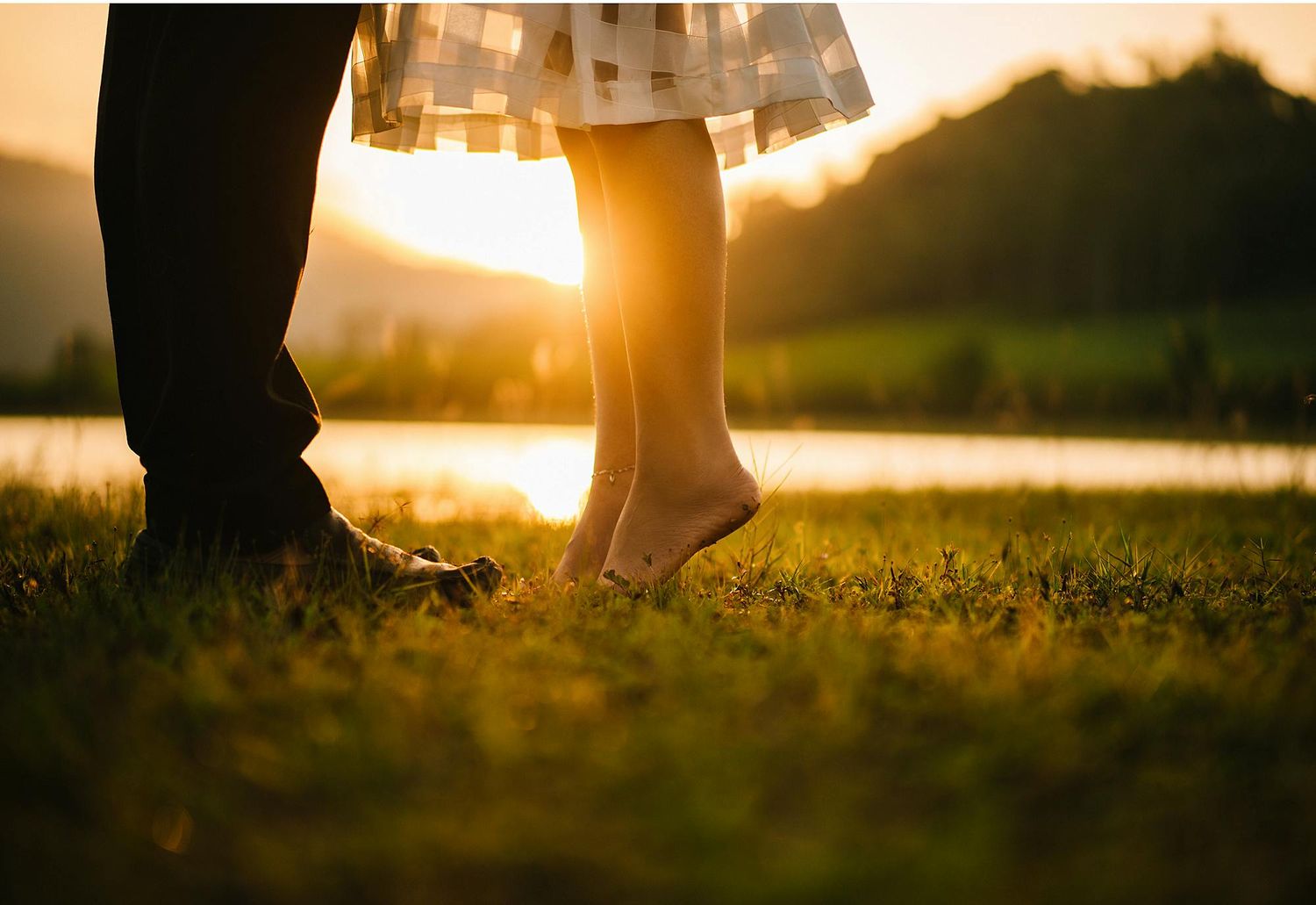 Couple photography at a park during golden hour where woman is in her tippy toes reaching for her boyfriend