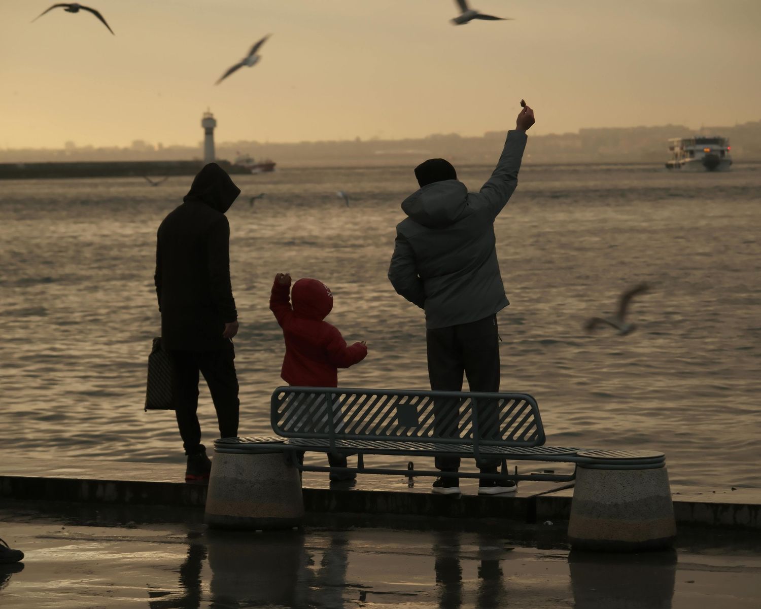 Family reaching to the sky at a harbor next to the sea posing for a family portrait session