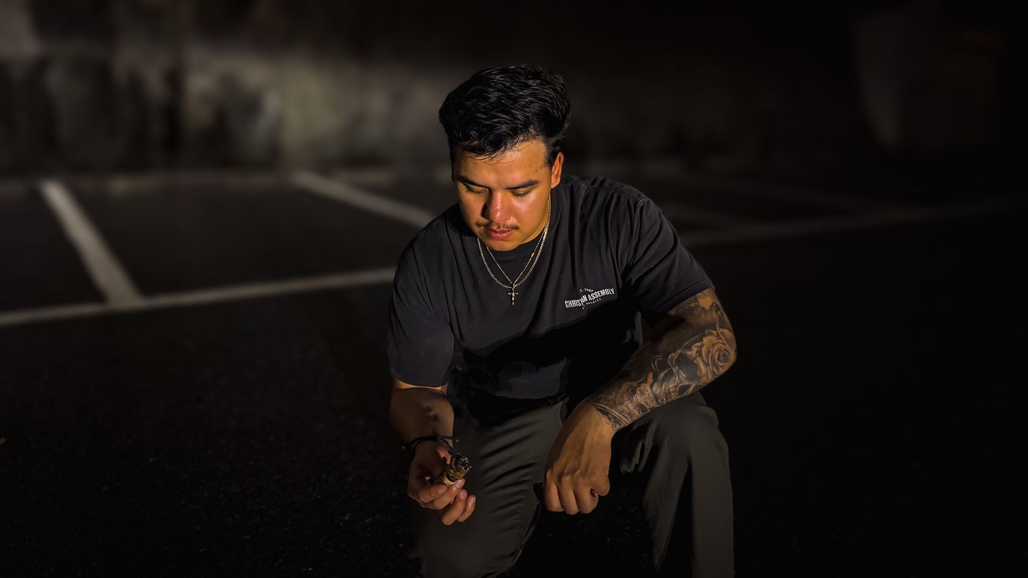Cinematic night portrait of a man crouching in low light with dramatic shadows