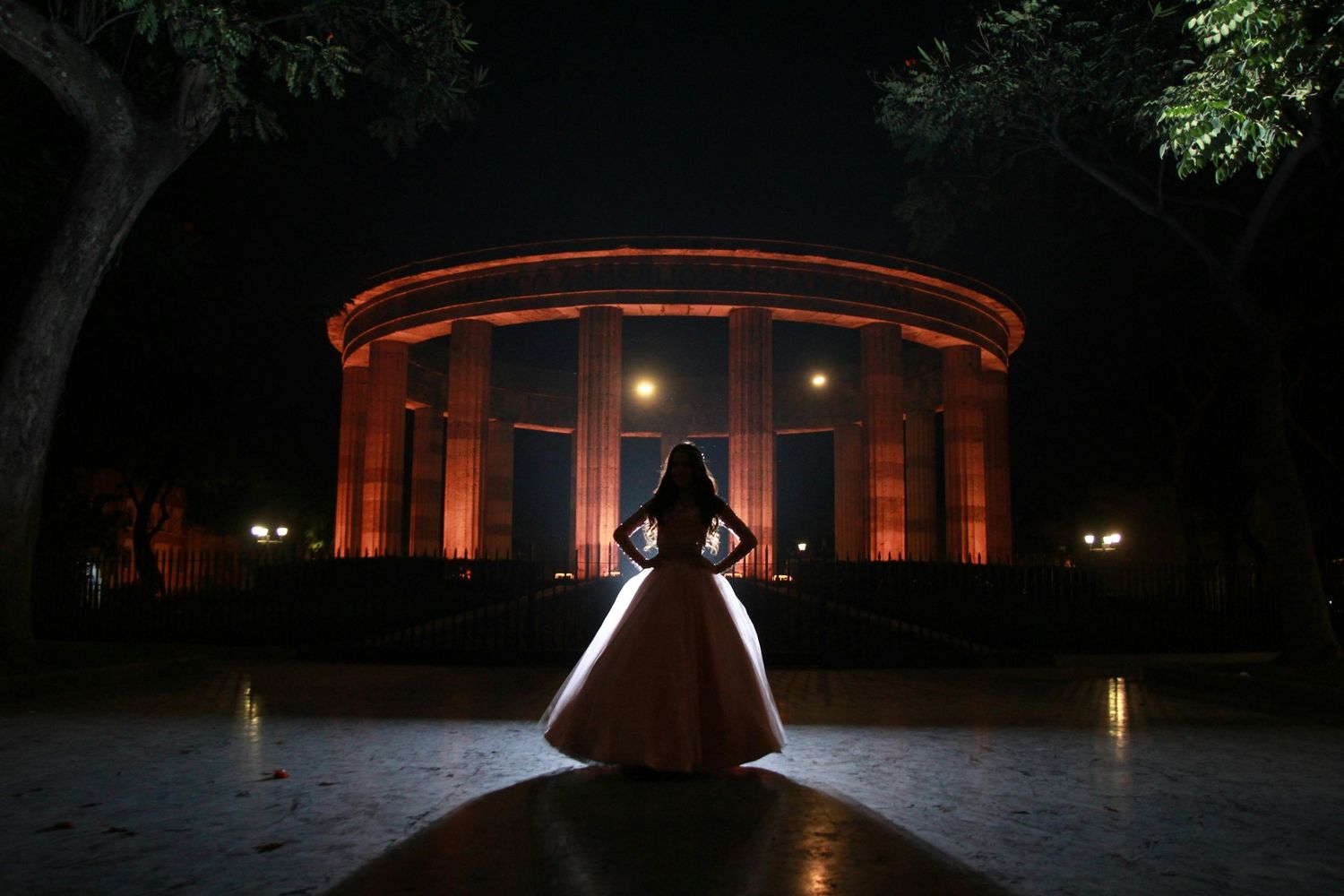 Cinematic low light at night quinceañera posing in front of a landmark for night photography