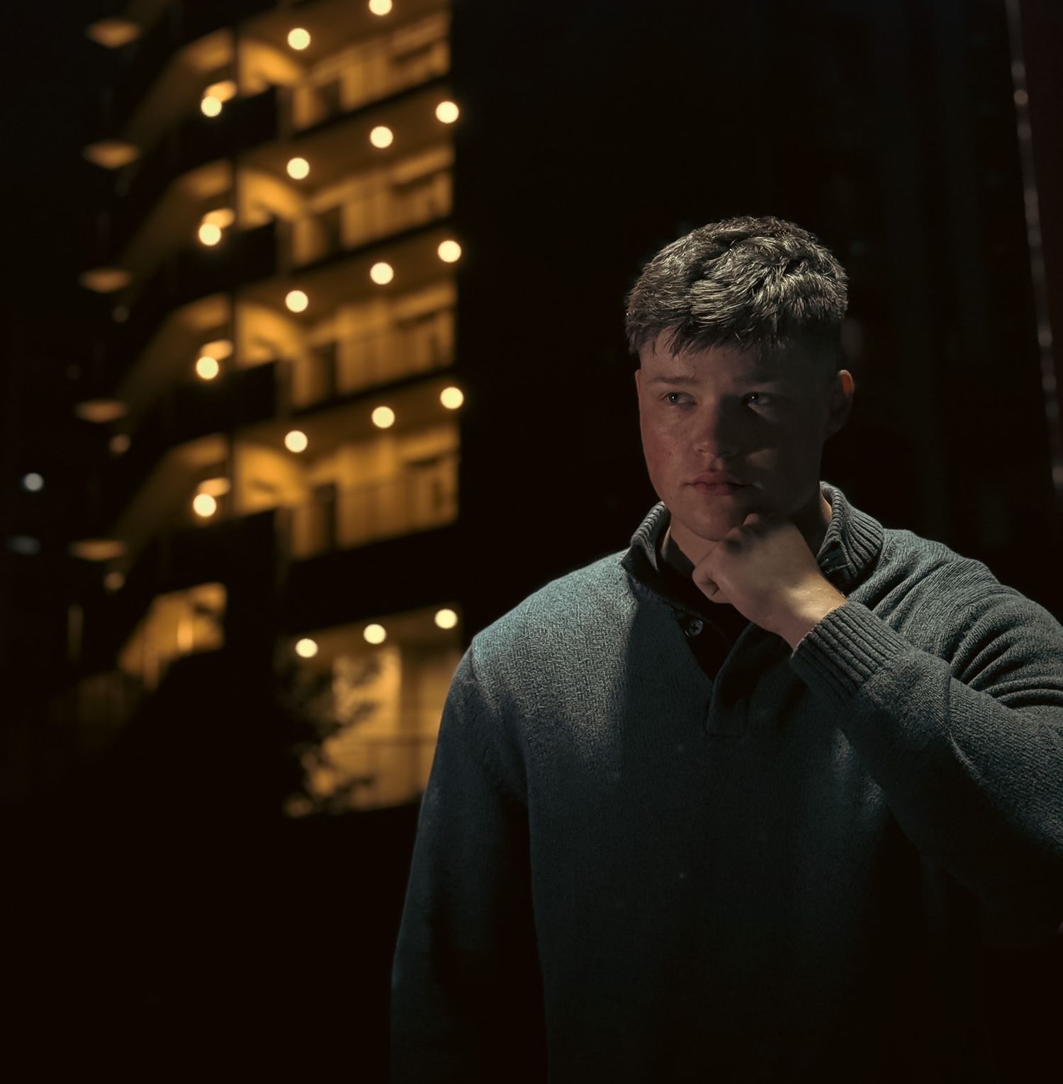 Night time portrait photo of a man with moody lighting and urban background
