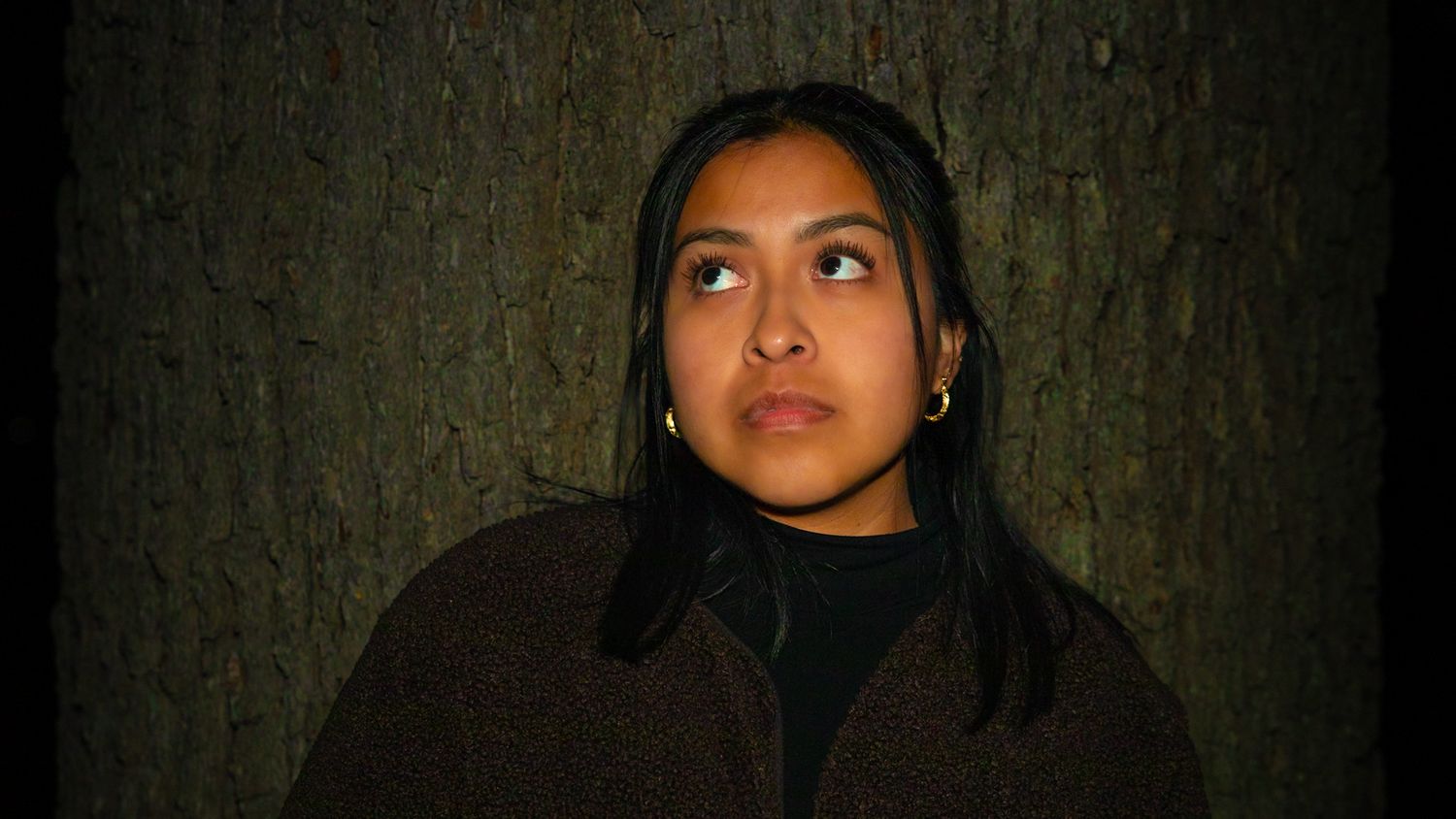 Cinematic headshot portrait of a woman looking upward with soft directional lighting and dark background