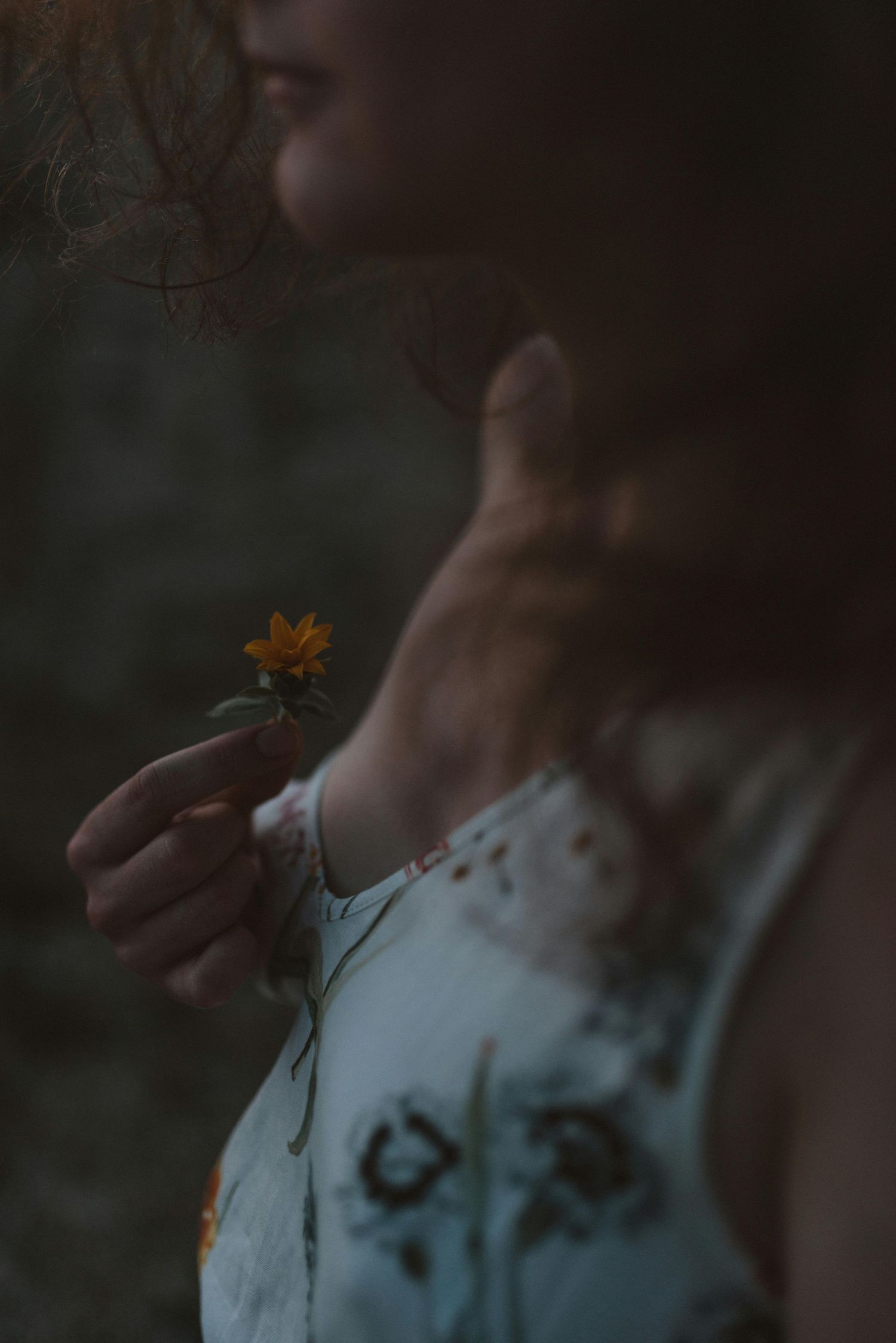 Artistic portrait of an individual holding a flower with soft natural light, emotional tone, and film style depth