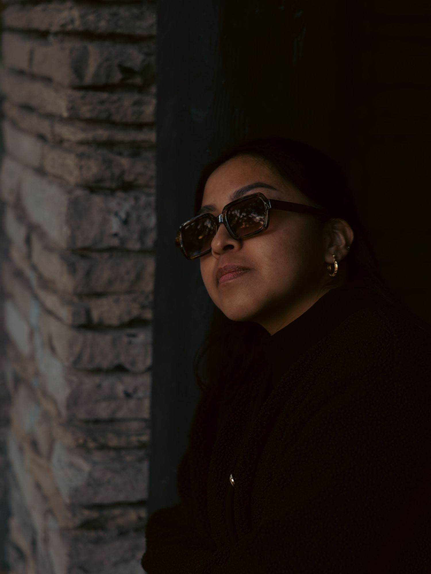 Portrait of a woman next to a stone wall with moody lighting
