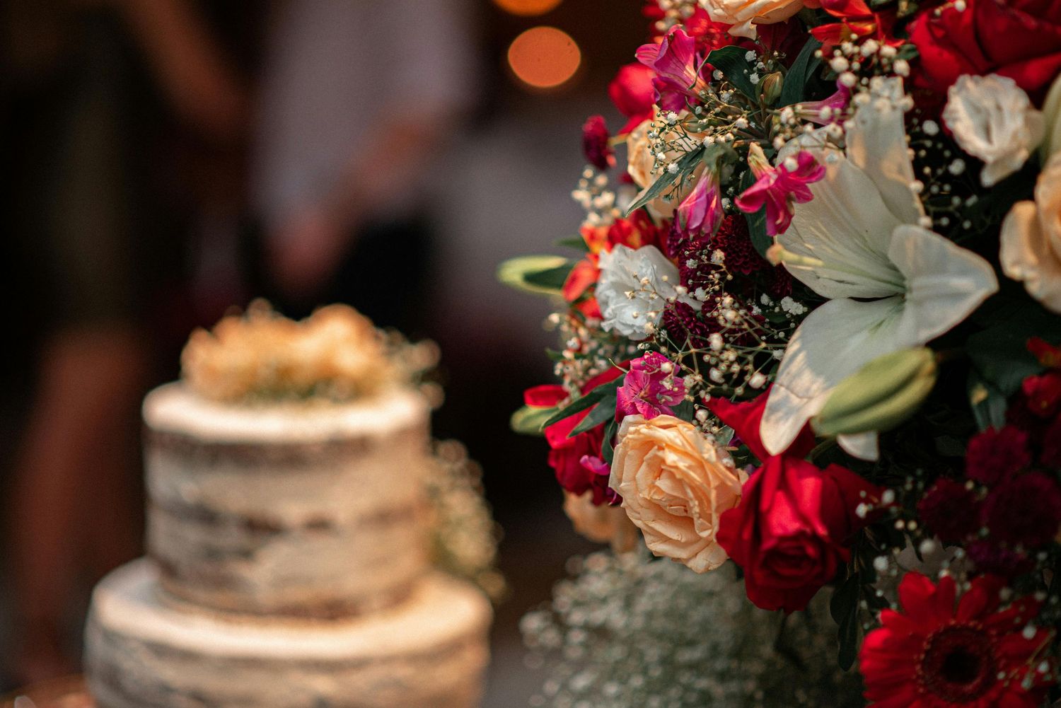 Detail photos of wedding capturing the flowers and the cake on the background in lowlight environment