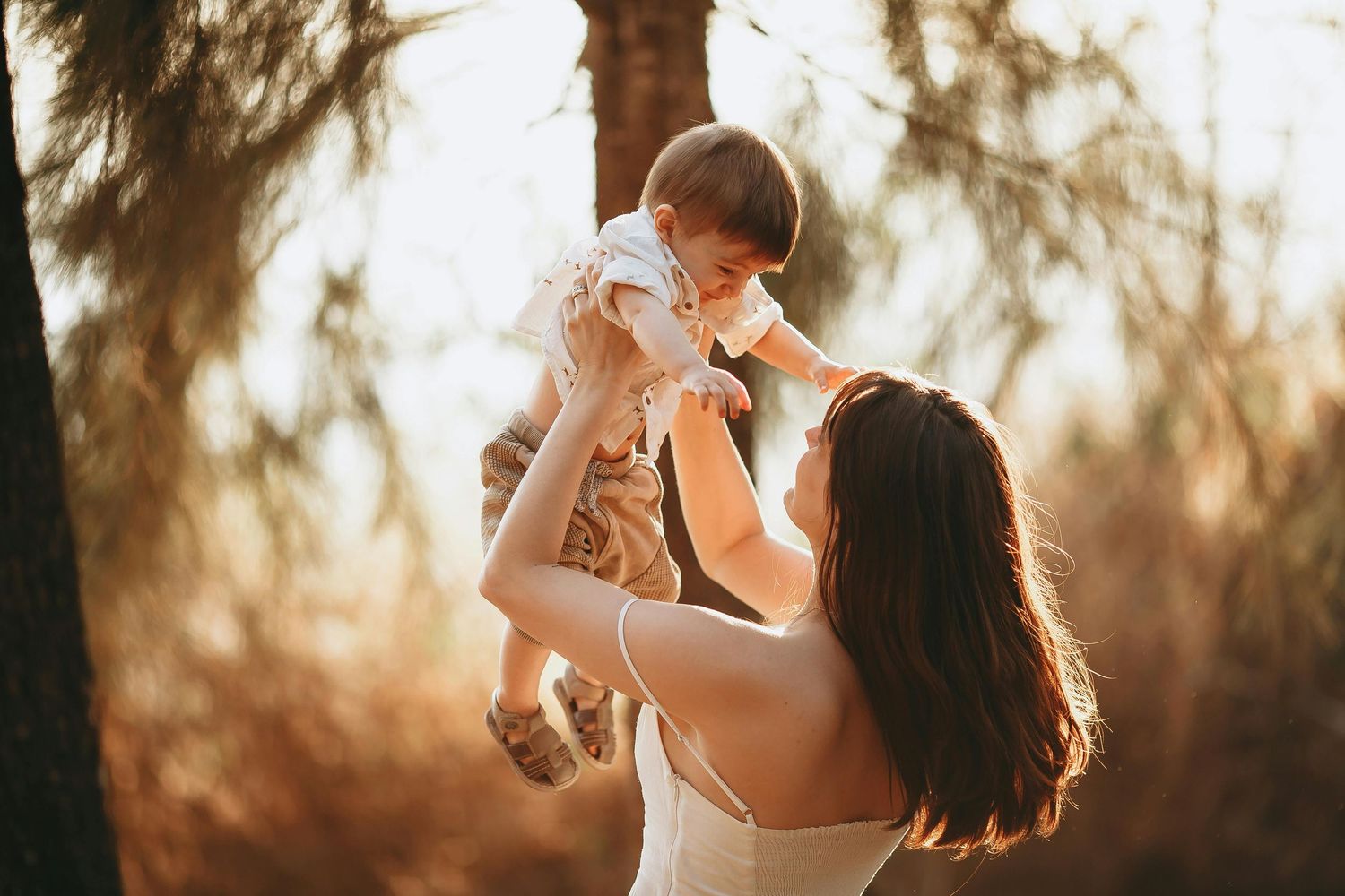 Family portrait with a mother lifting her child in warm golden hour