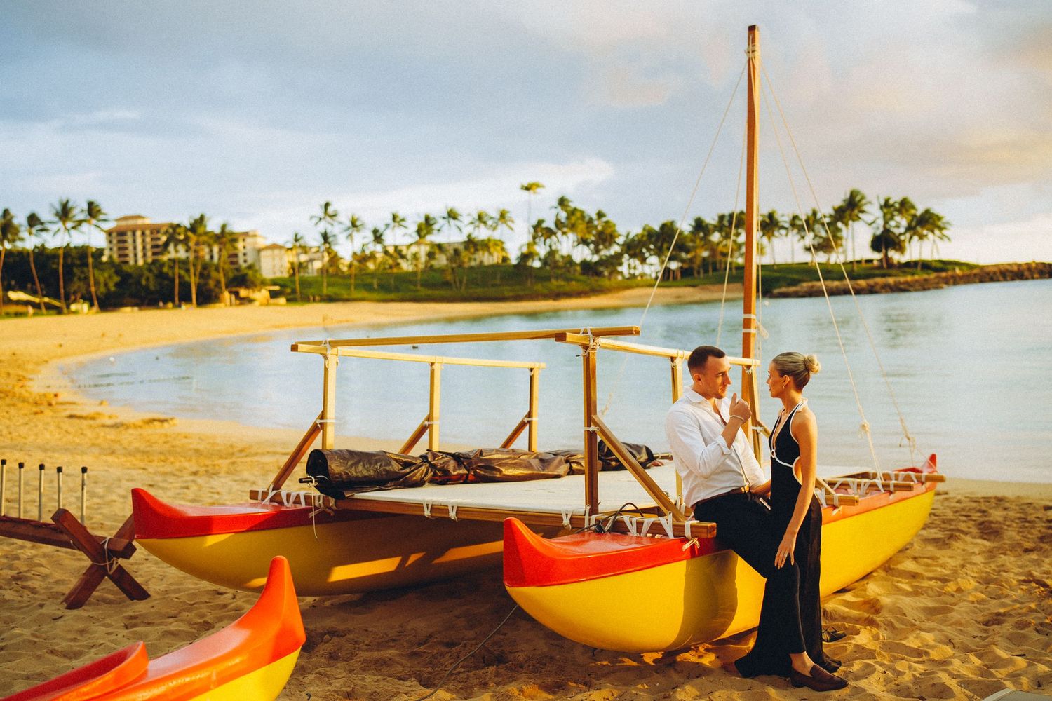 Ko Olina proposal. Colorful outrigger canoes line the sandy beach at sunset with palm trees and ocean in the background.