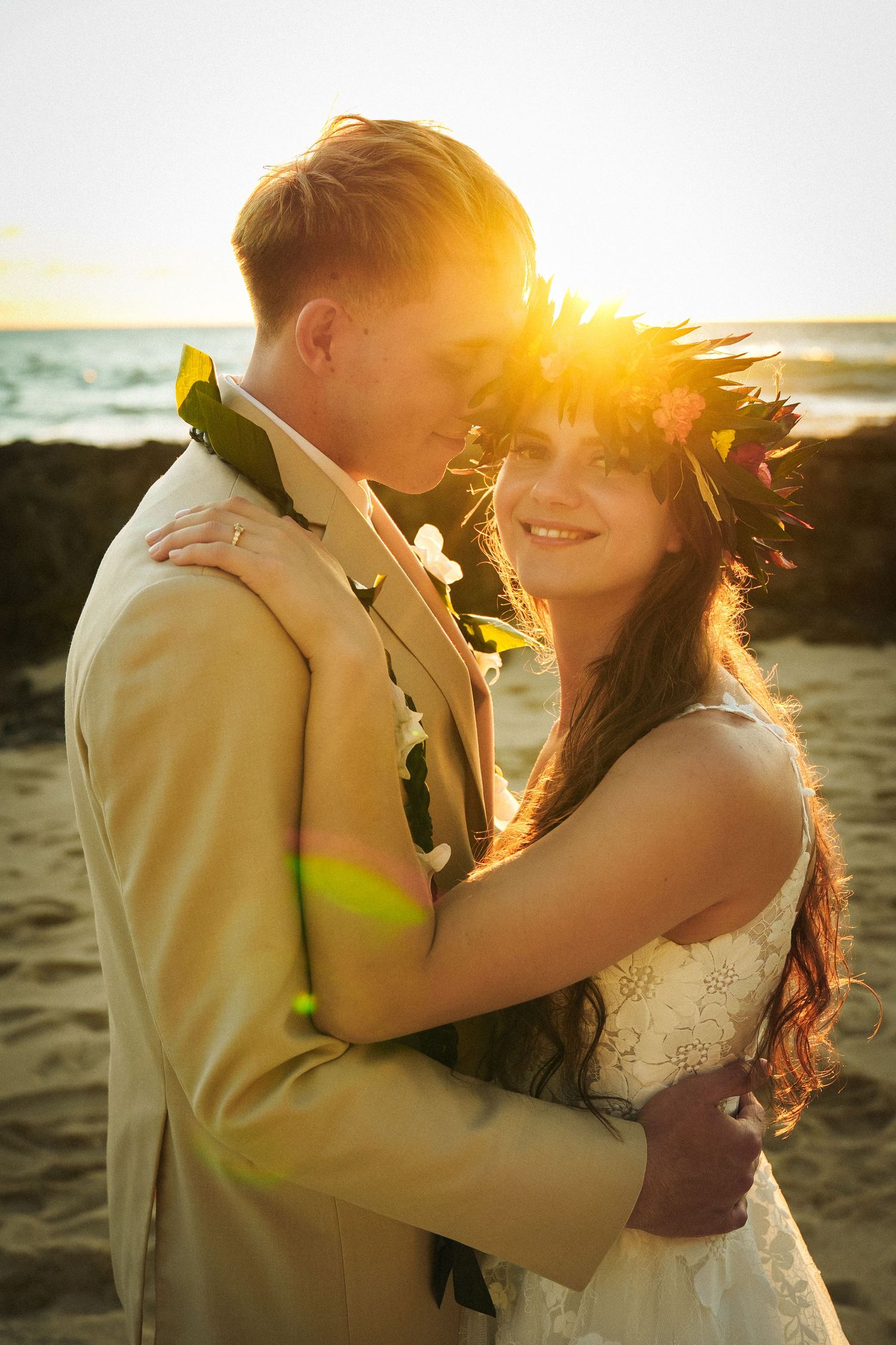 Close-up of a groom hugging his bride during a sunset wedding session on the Hawaii coast.