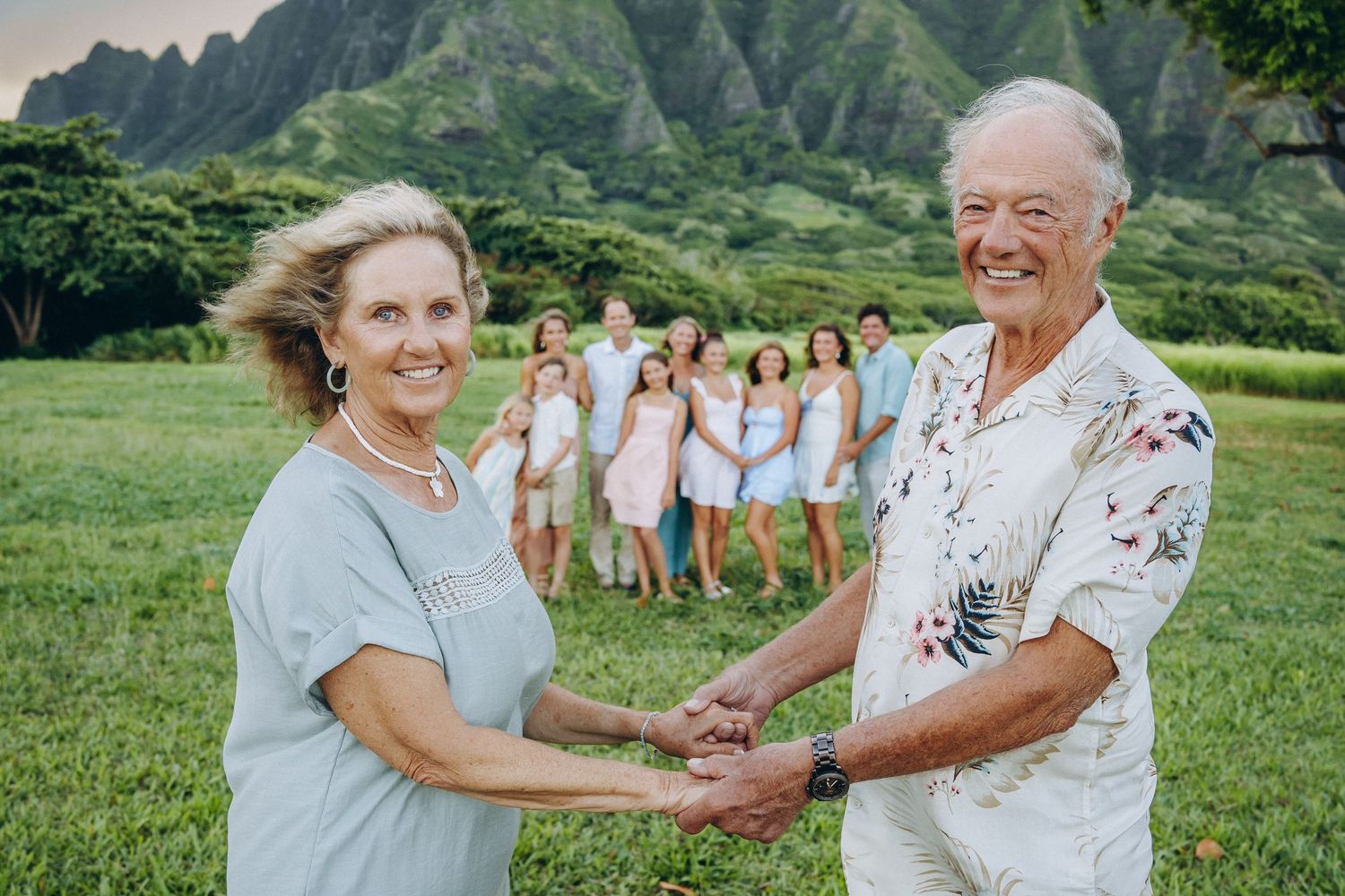 Grandparents holding hands with grandchildren gathered in a circle behind them, Kualoa Ranch Oahu family photographer