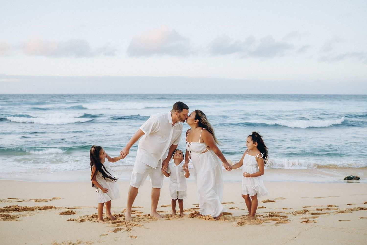 Parents kissing on the shore with their kids at Sandy Beach, Oahu family photographer, Hawaii beach session