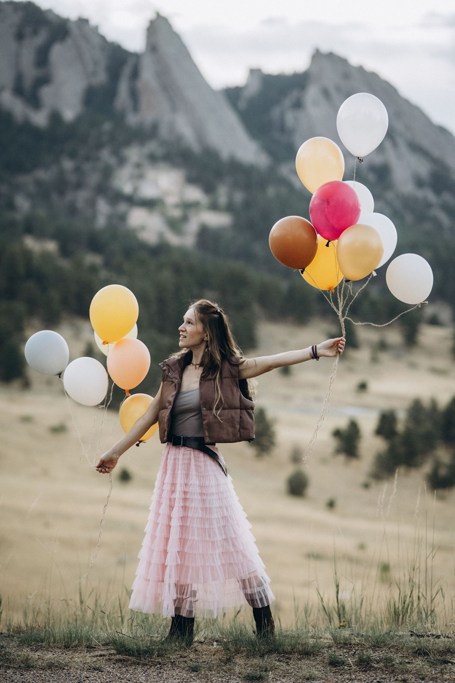 Girl walking through golden grass with balloons at NCAR, Boulder Colorado family photography session