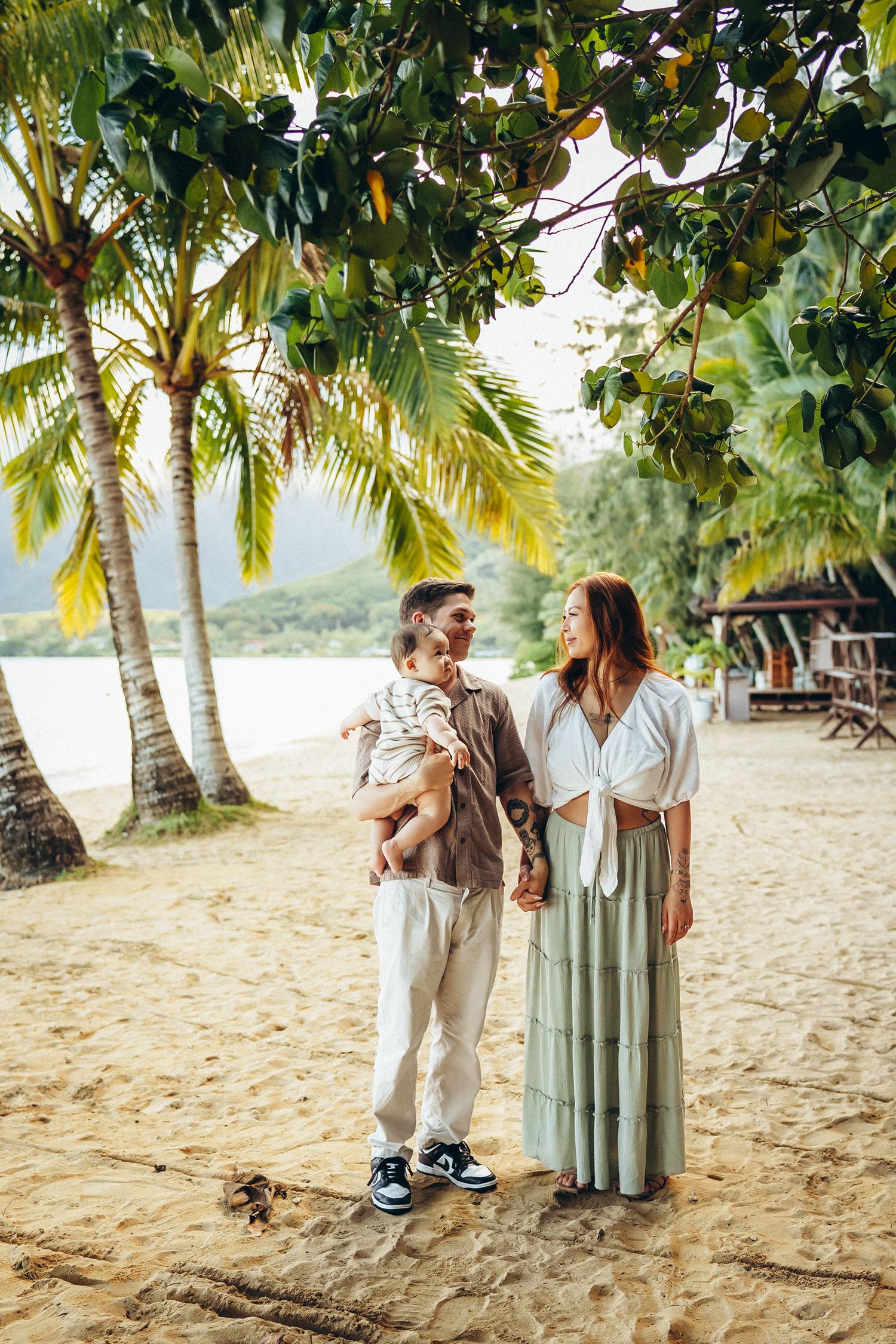 Professional photographer in Oahu. A couple walking through lush trees at Secret Beach near Kualoa Ranch. Tropical family session.