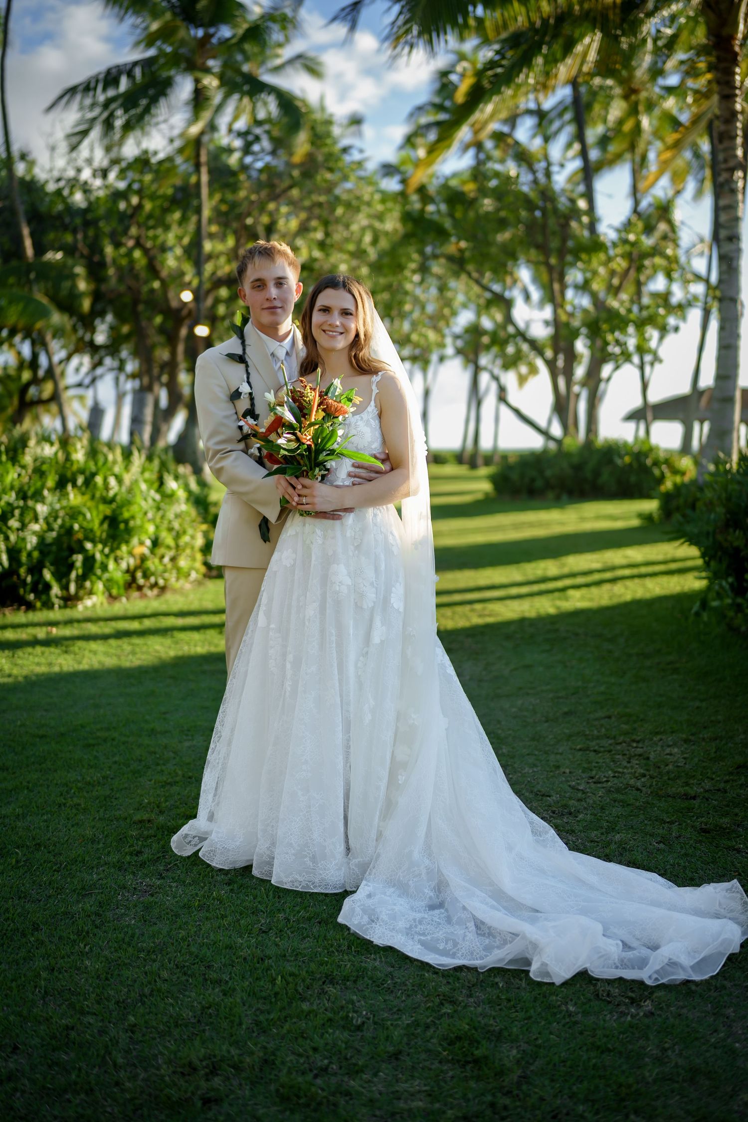 A graceful full-length portrait of the bride and groom set against a lush backdrop of palm groves. This shot captures the upscale and serene