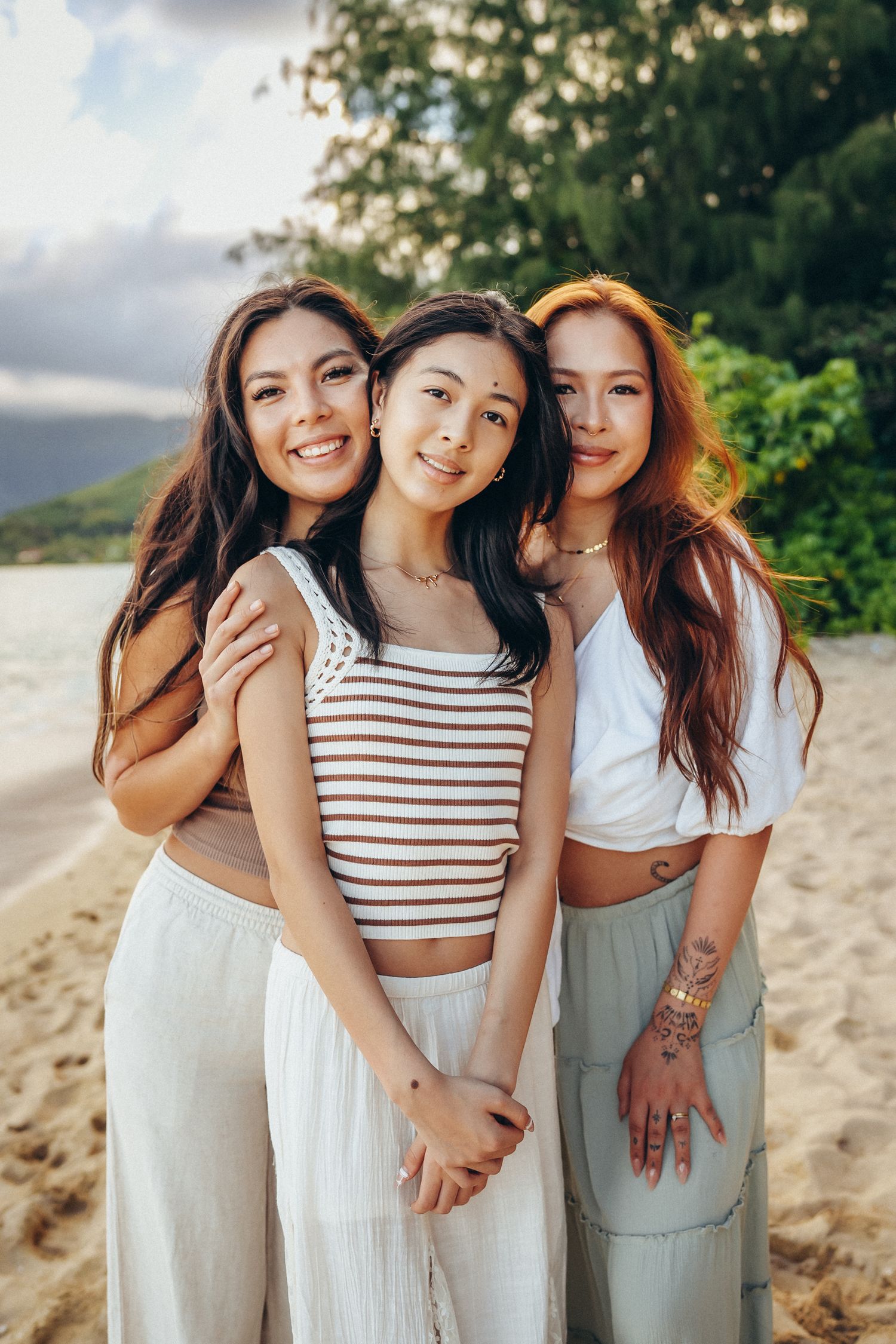 Professional photographer in Oahu. Three sisters smiling during a family photoshoot at Secret Beach near Kualoa Ranch. Pure joy!