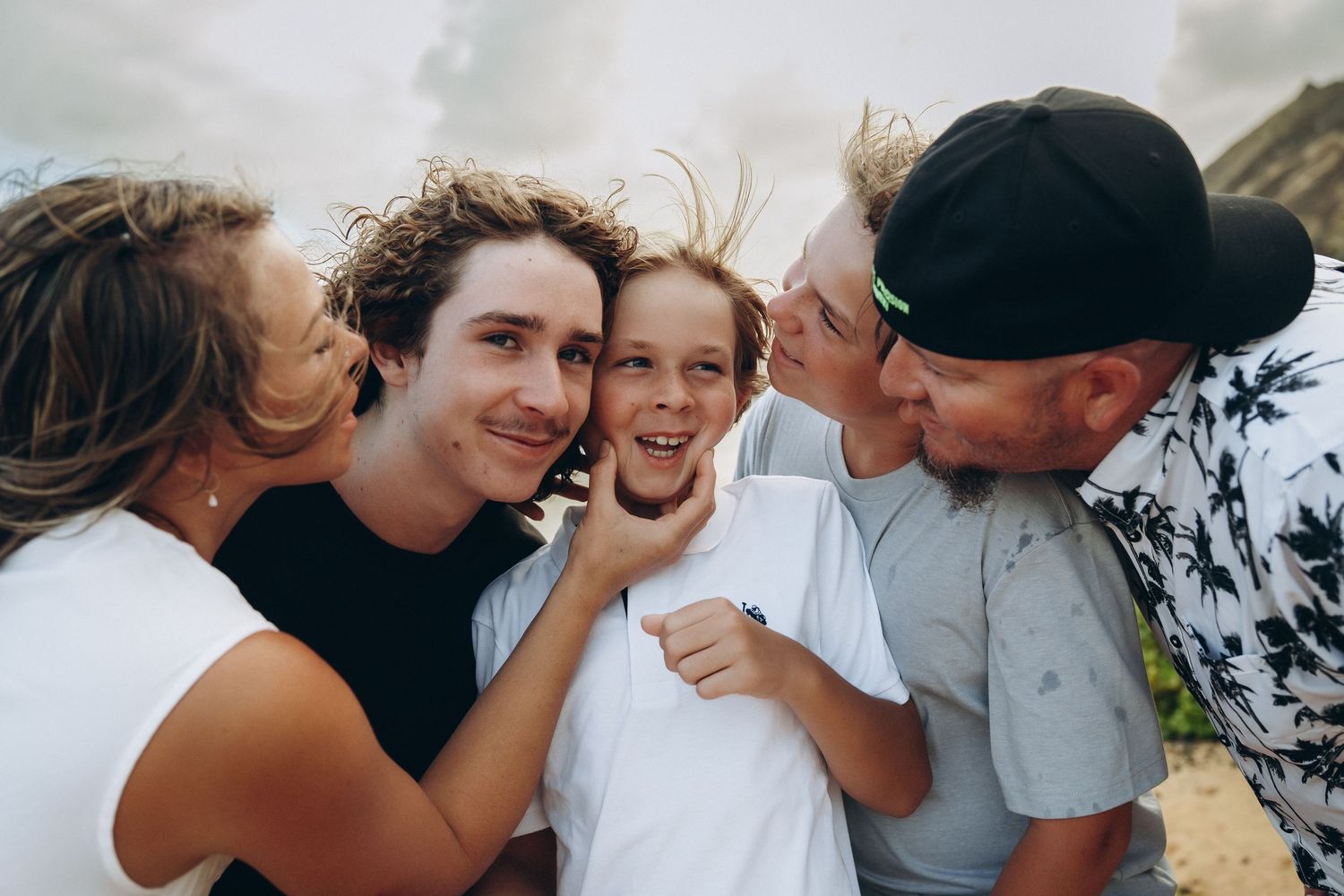 Parents kissing their laughing kids on the cheeks, Sandy Beach Oahu family photographer, Hawaii family session