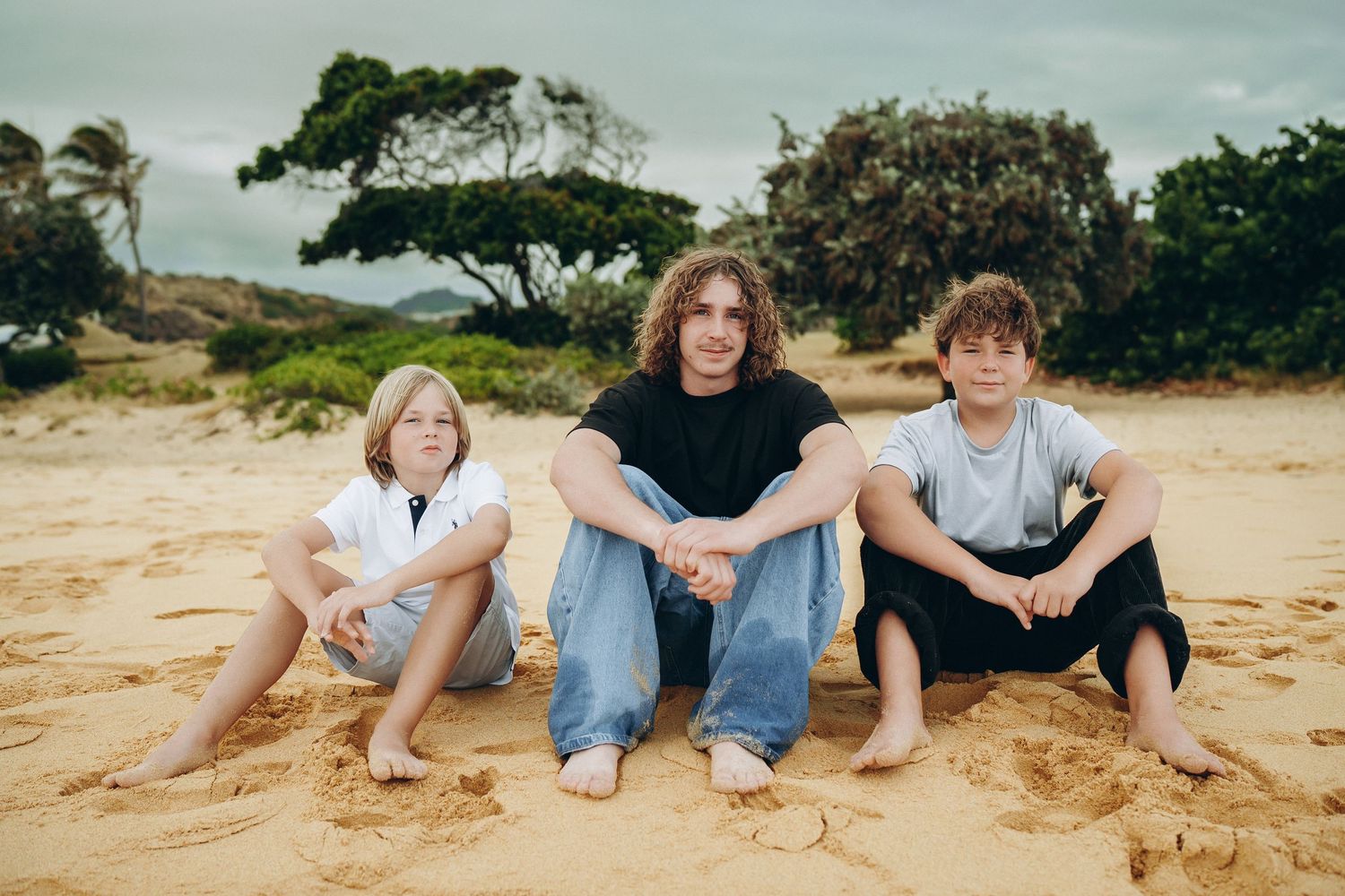 Three siblings sitting together on the sand at Sandy Beach, Oahu family photographer, Hawaii family session