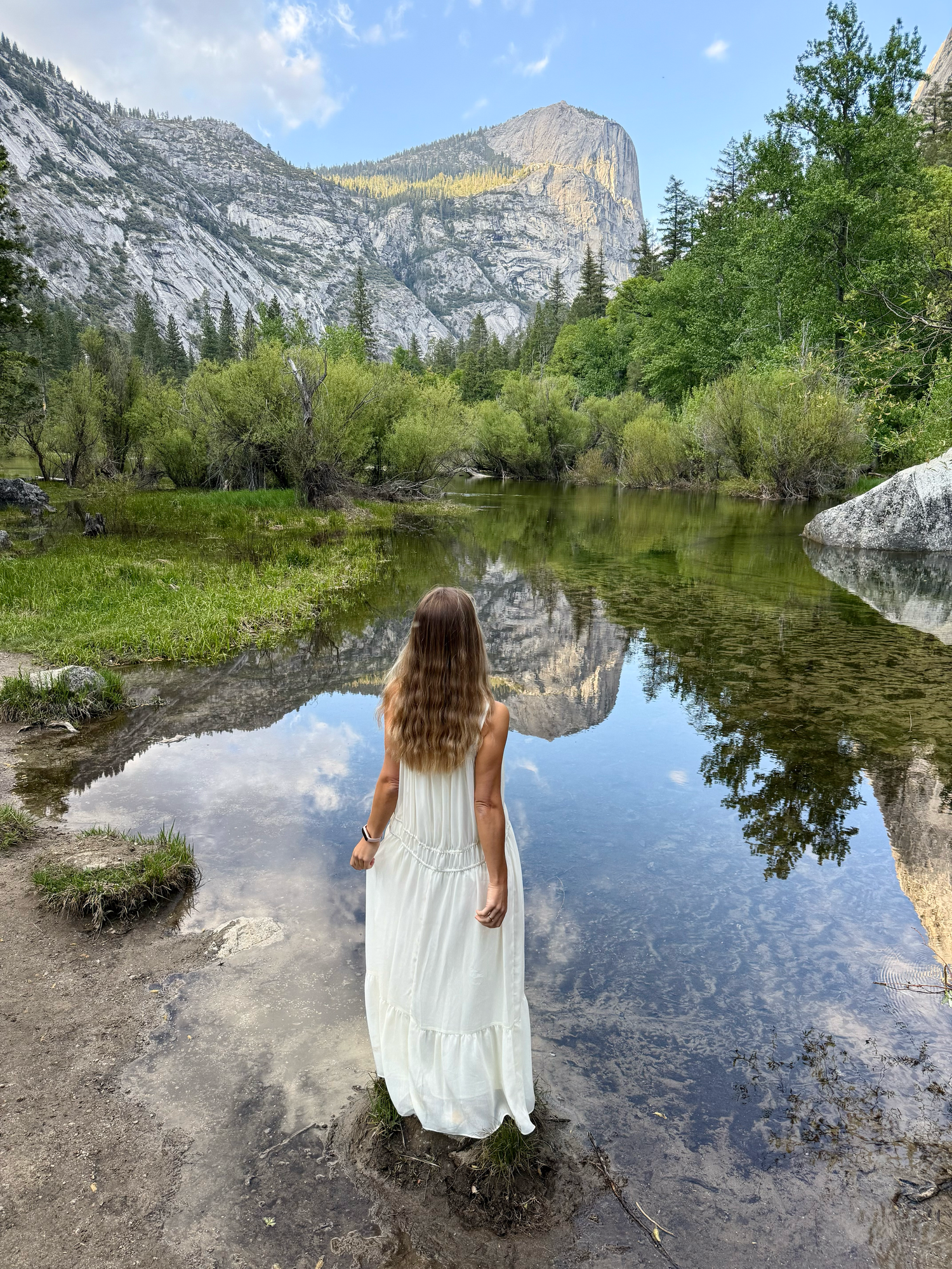 Scenic view of Mirror Lake in Yosemite National Park with Half Dome mountain reflecting in still waters on a sunny day.