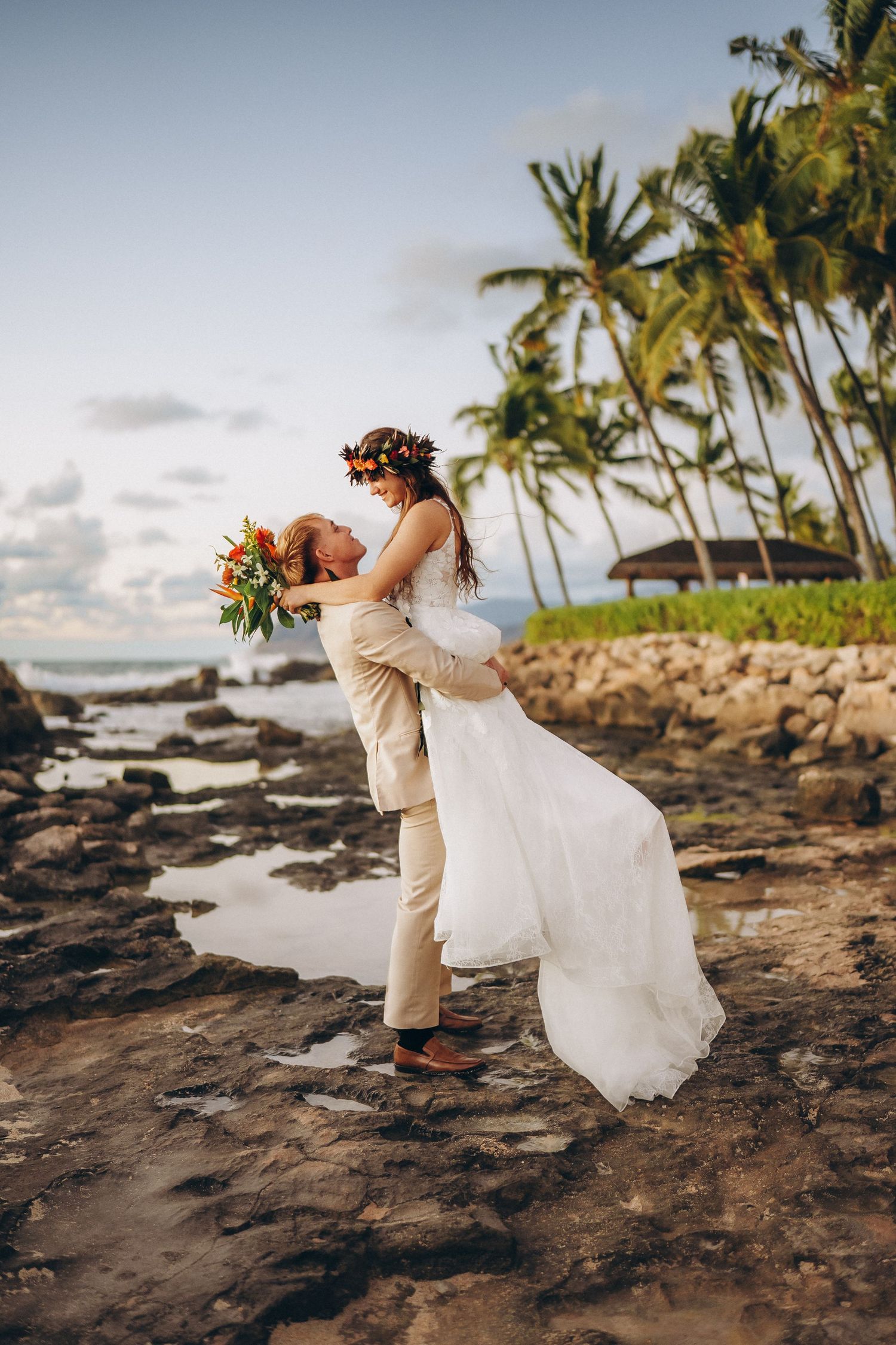 Bride and groom on the volcanic rocks at Pohaku Point, Four Seasons Oahu. Dramatic wedding photography at Ko Olina shoreline.