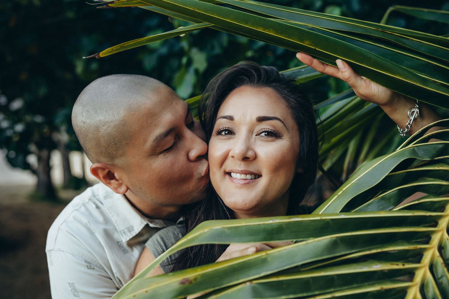 Secret Beach family photoshoot, Oahu. Romantic couple portrait under palm leaves at Kualoa Ranch. Professional lifestyle photography.