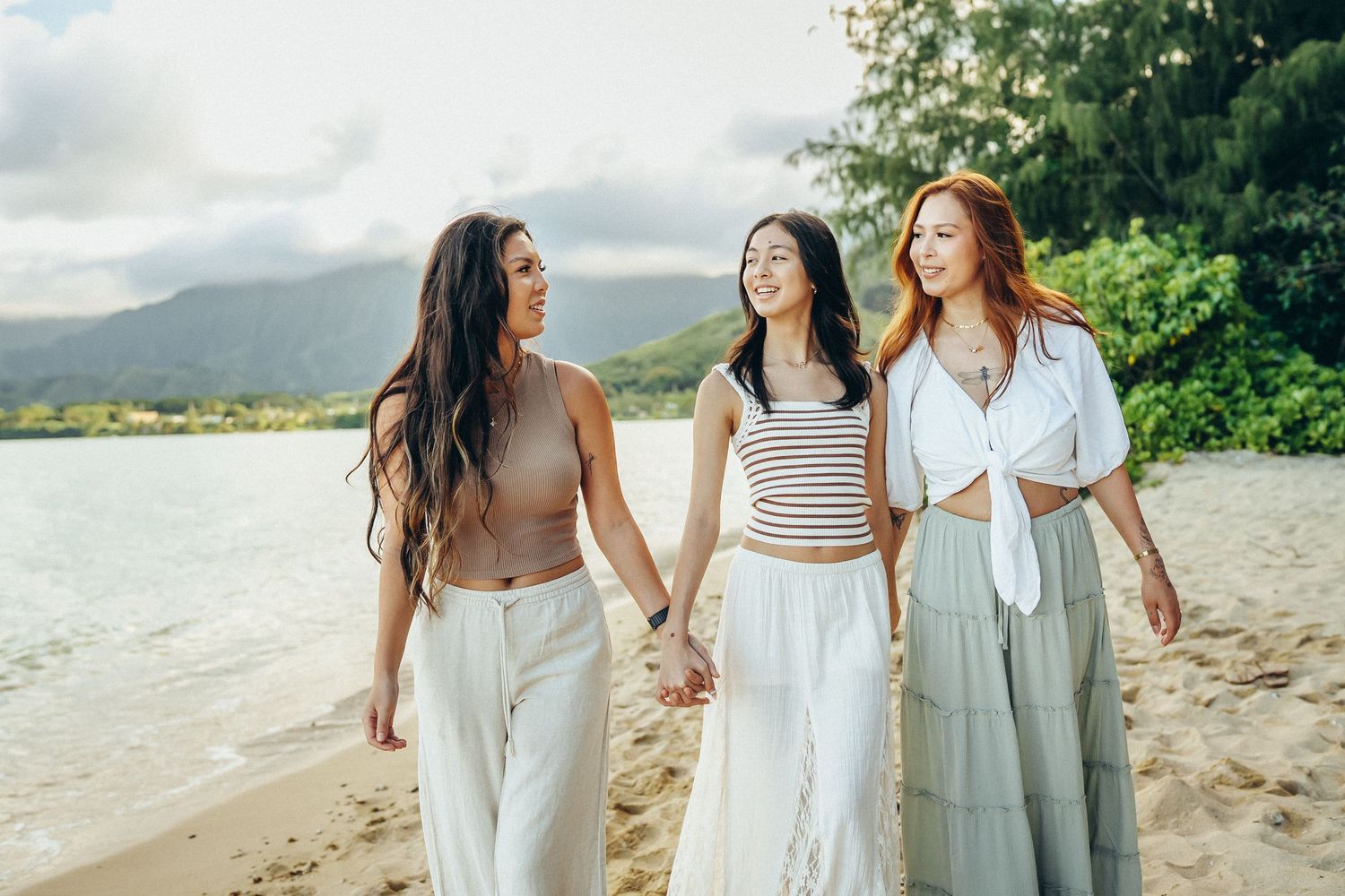 Beautiful Oahu family photoshoot. Three sisters walking along the shoreline at Secret Beach near Kualoa Ranch. Tropical vibes.