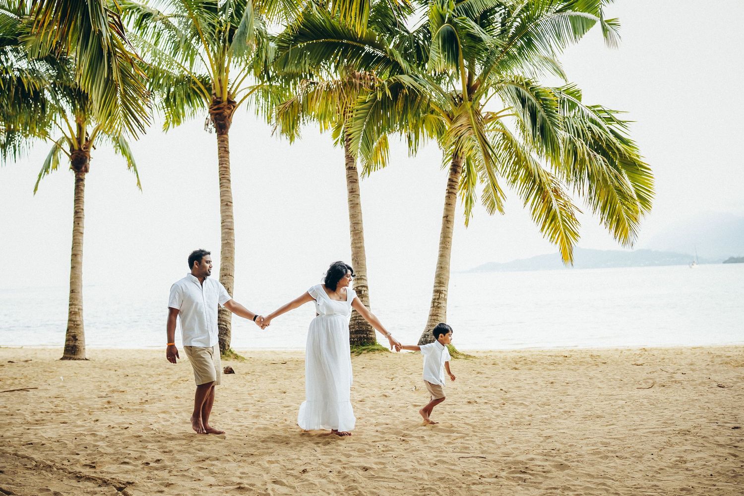 Family photoshoot at Secret Beach, Oahu. A happy family walking along the sandy shore near Kualoa Ranch. Beautiful tropical scenery.