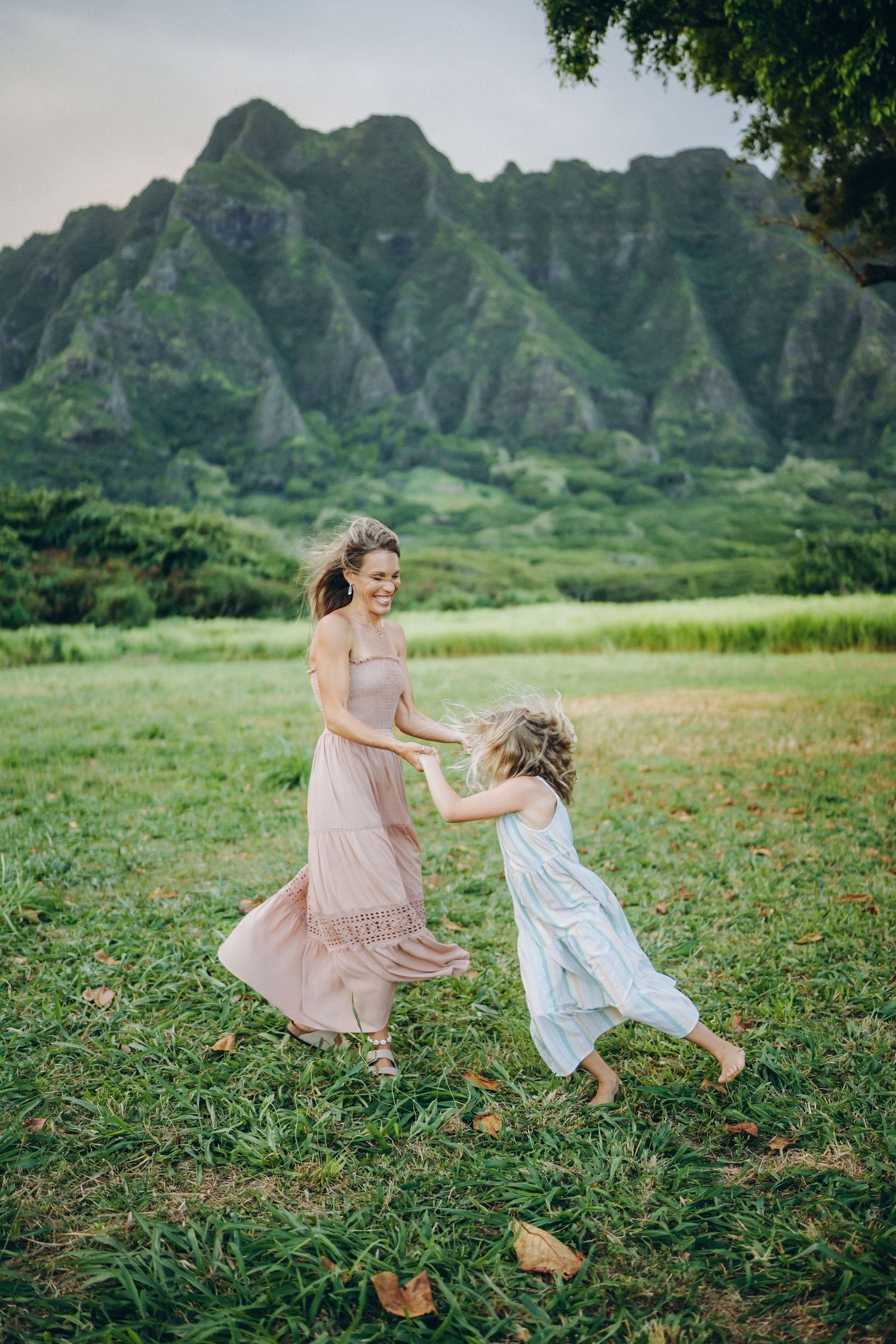 Mom twirling with her little girl on the lawn, mountains behind, Kualoa Ranch Oahu family photographer, Hawaii