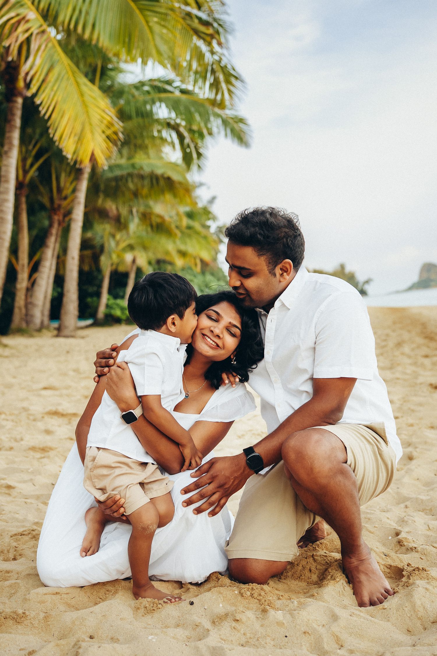 Oahu family photoshoot at Secret Beach. A family sitting together on the sand near Kualoa Ranch. Warm sunset light and island vibes.