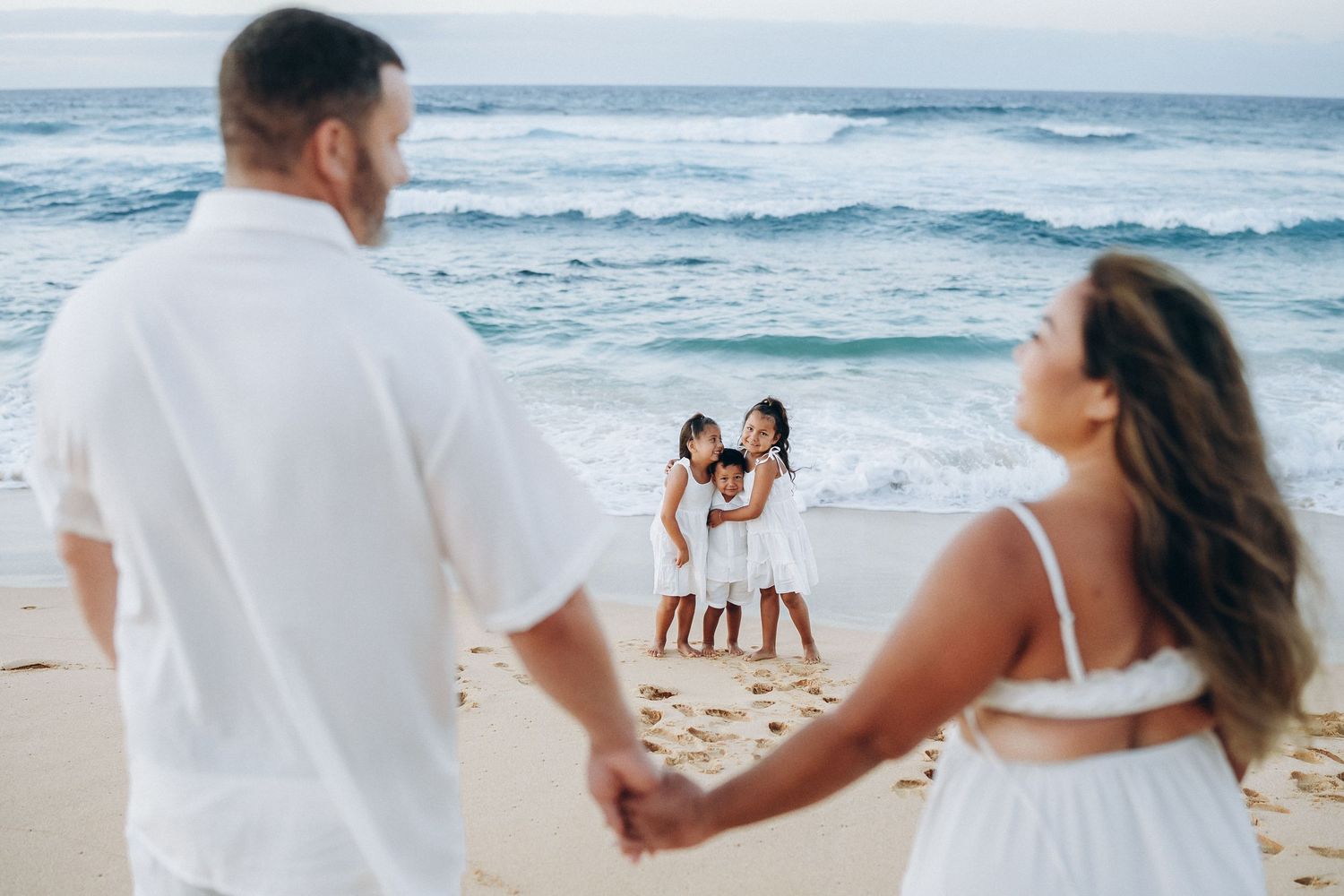 Parents holding hands on the shore with their kids ahead, Sandy Beach Oahu family photographer, Hawaii
