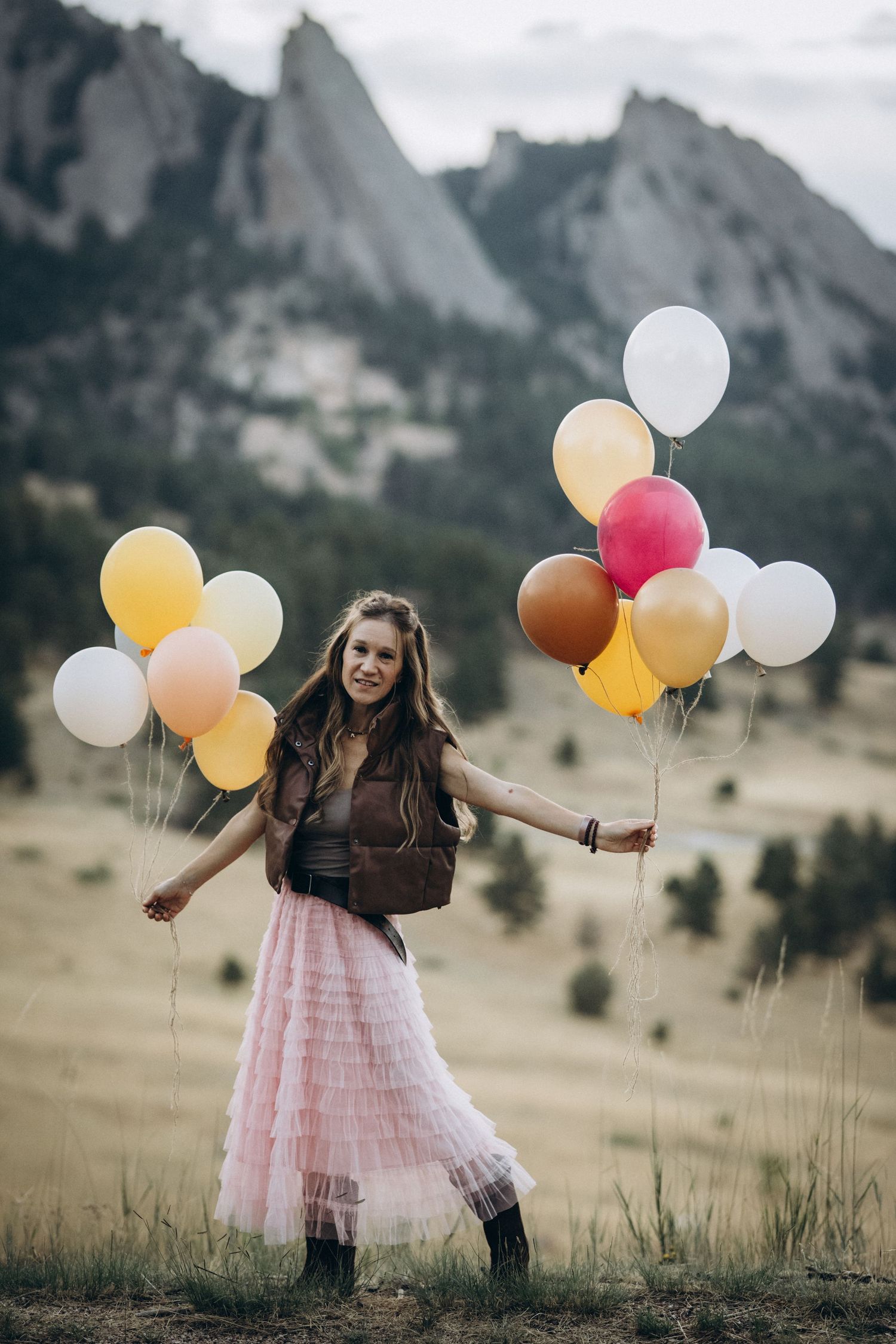Girl in pink tulle skirt with balloons in a meadow below the Flatirons, Boulder family photography at NCAR, Colorado