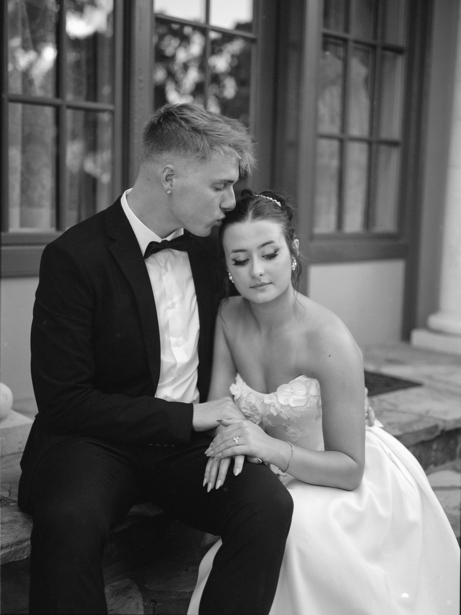 A romantic black and white wedding photo series showing a couple sitting together on outdoor steps in formal attire.